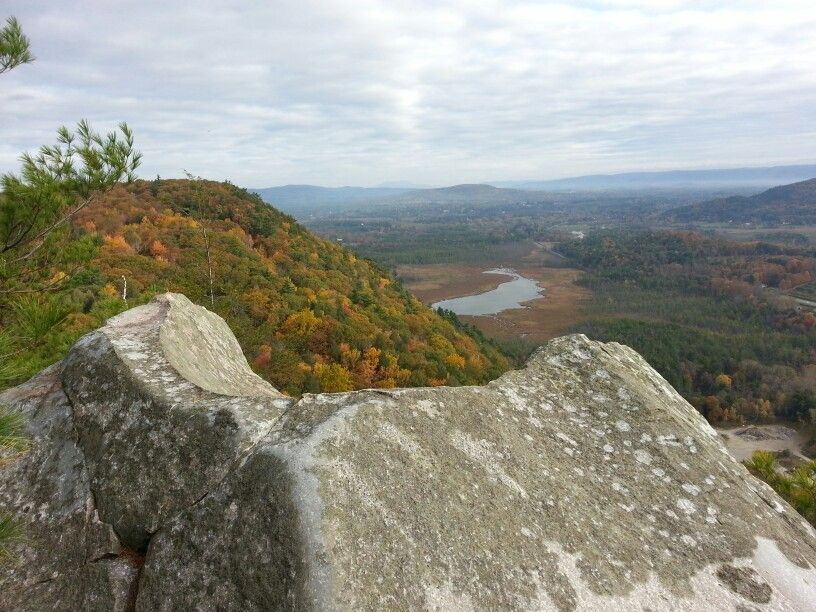 A rocky mountain overlook with vibrant autumn trees, a valley, and a lake below. - Hickey and Peeskawso Peak Loop
