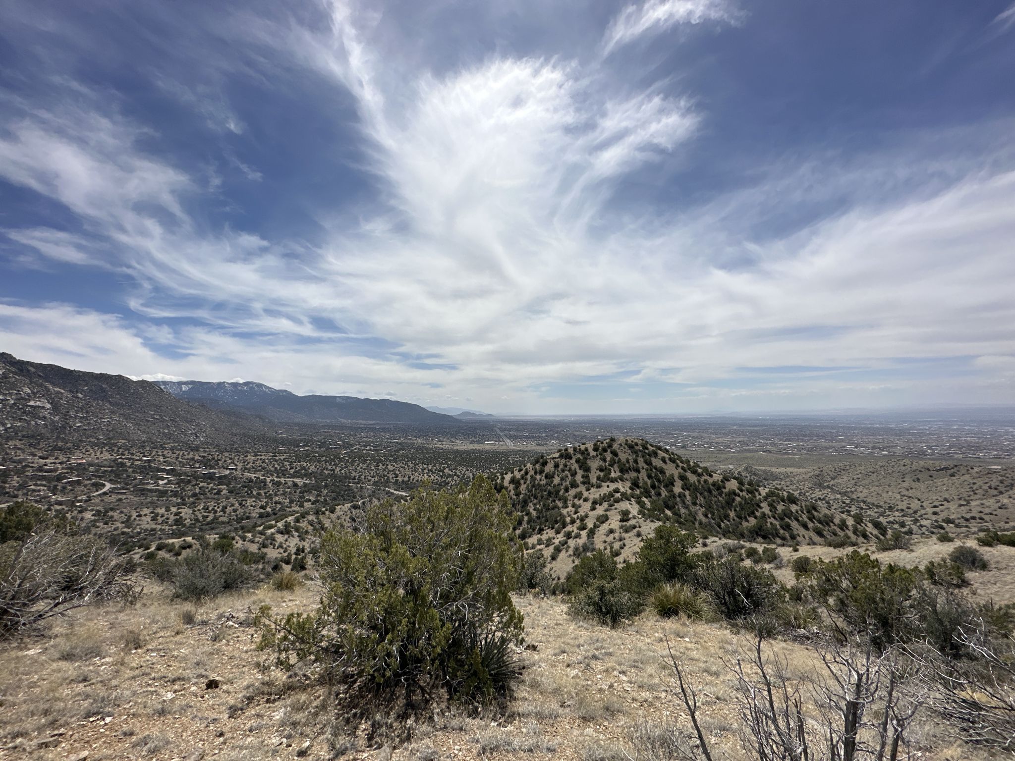 Expansive dry, hilly landscape with distant mountains under a partly cloudy sky. - Juan Tabo Canyon Loop