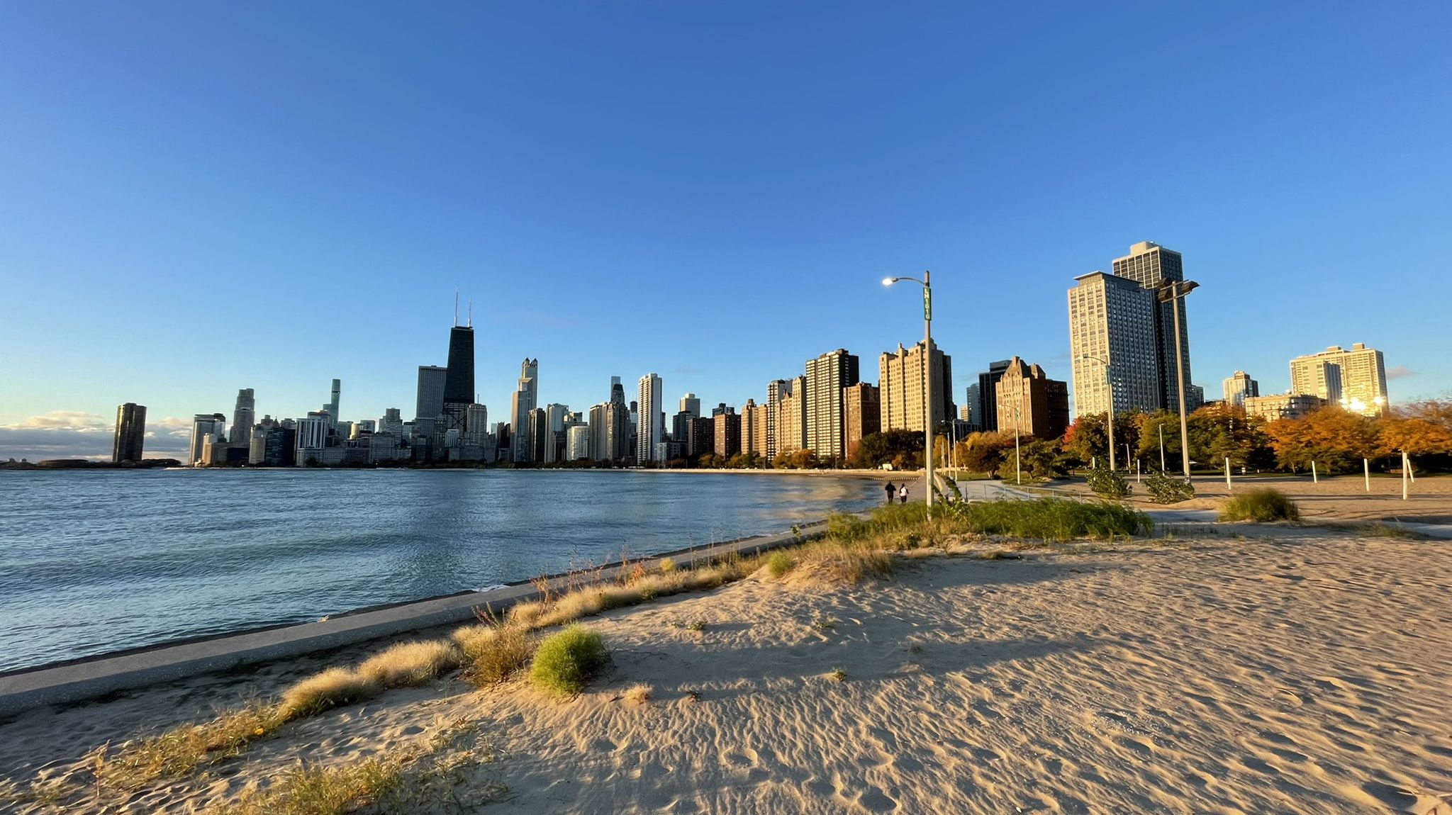 City skyline across a large lake from a sandy beach at golden hour. - Lincoln Park and Lakefront Trail Loop