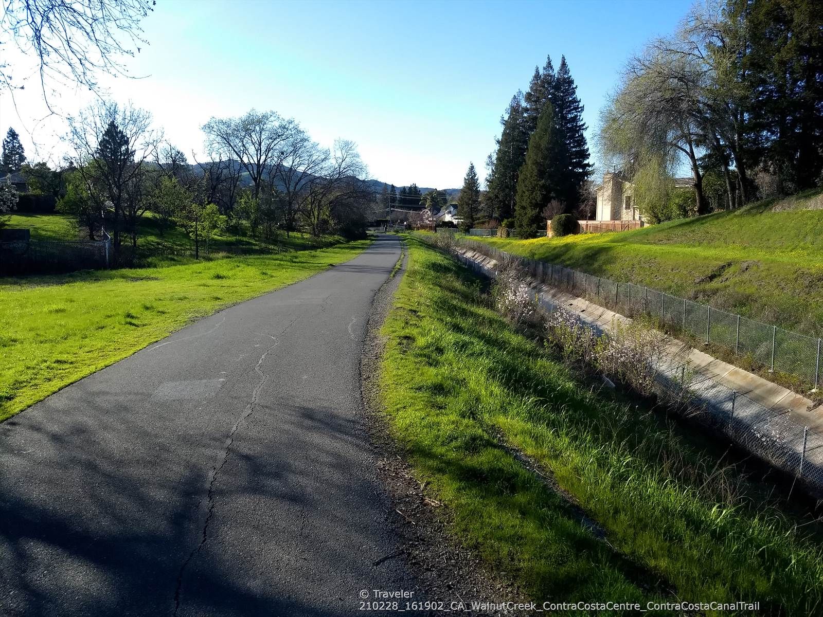 Paved path next to a fenced canal with vibrant green grass. - Iron Horse Trail – Iron Horse Trail junction loop from Concord