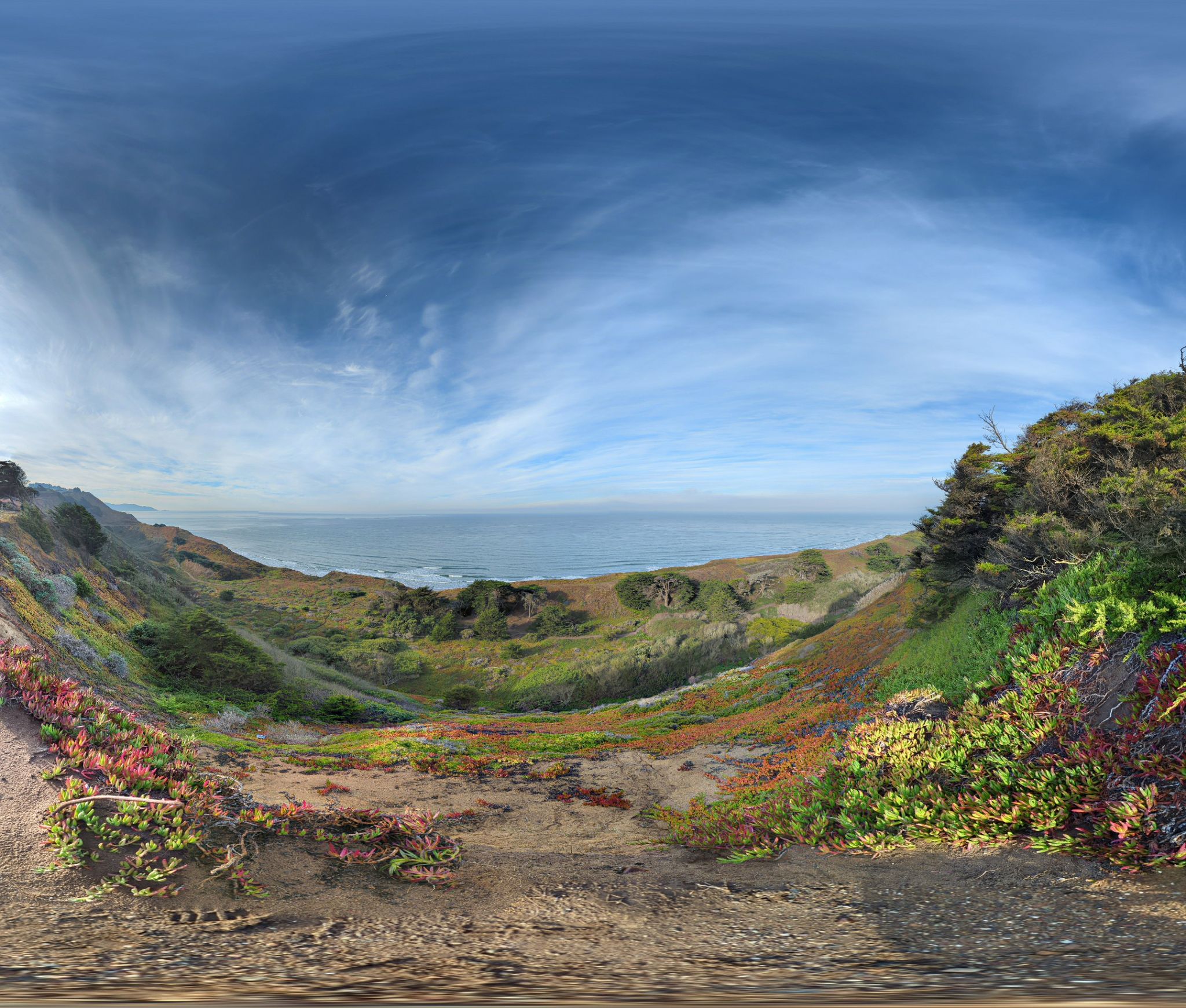 Panoramic view of green and brown coastal hills meeting the ocean under a cloudy sky. - Thornton Beach Trail