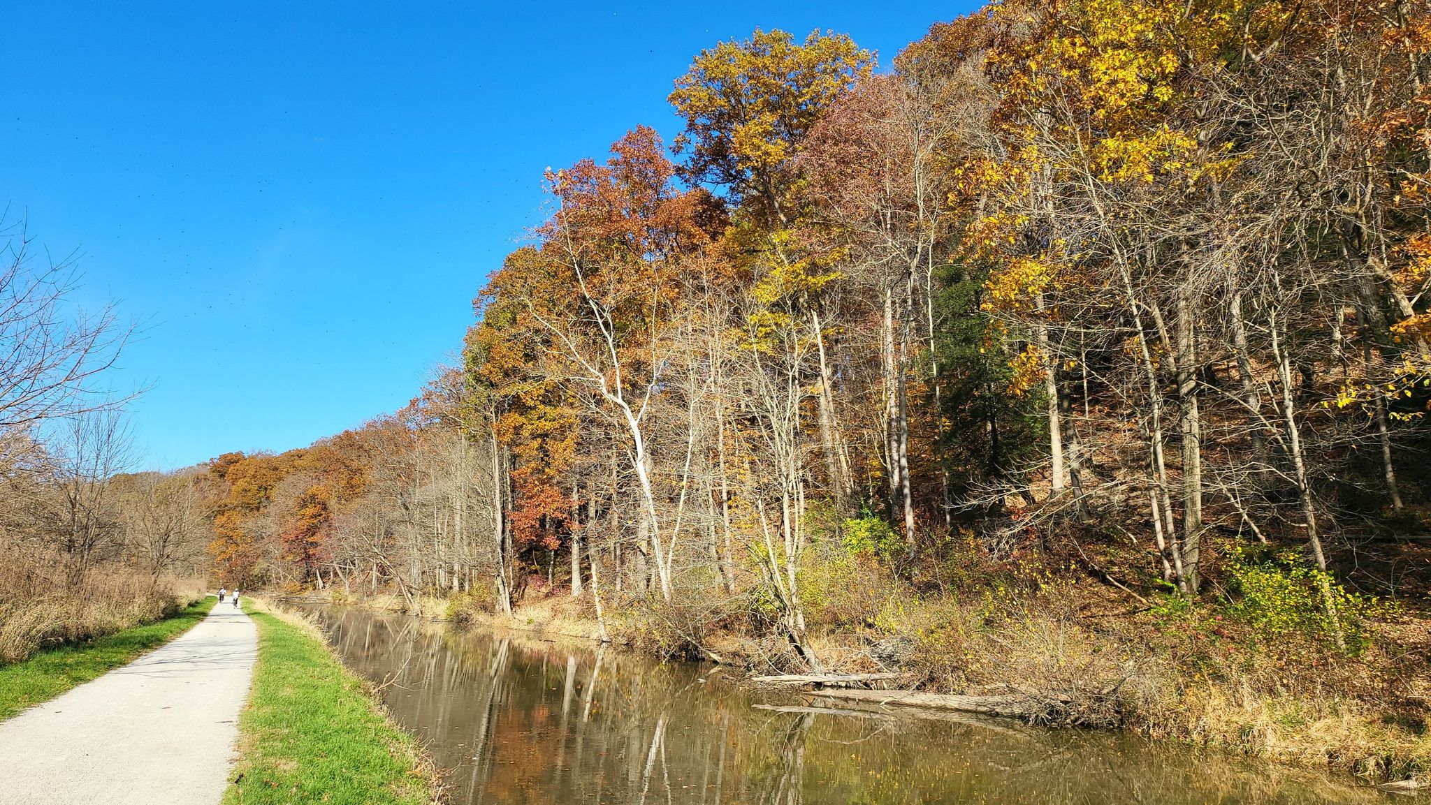 Paved path runs beside a calm river, bordered by vibrant autumn trees. - Ohio and Erie Canal Towpath: Rockside to Brecksville Station