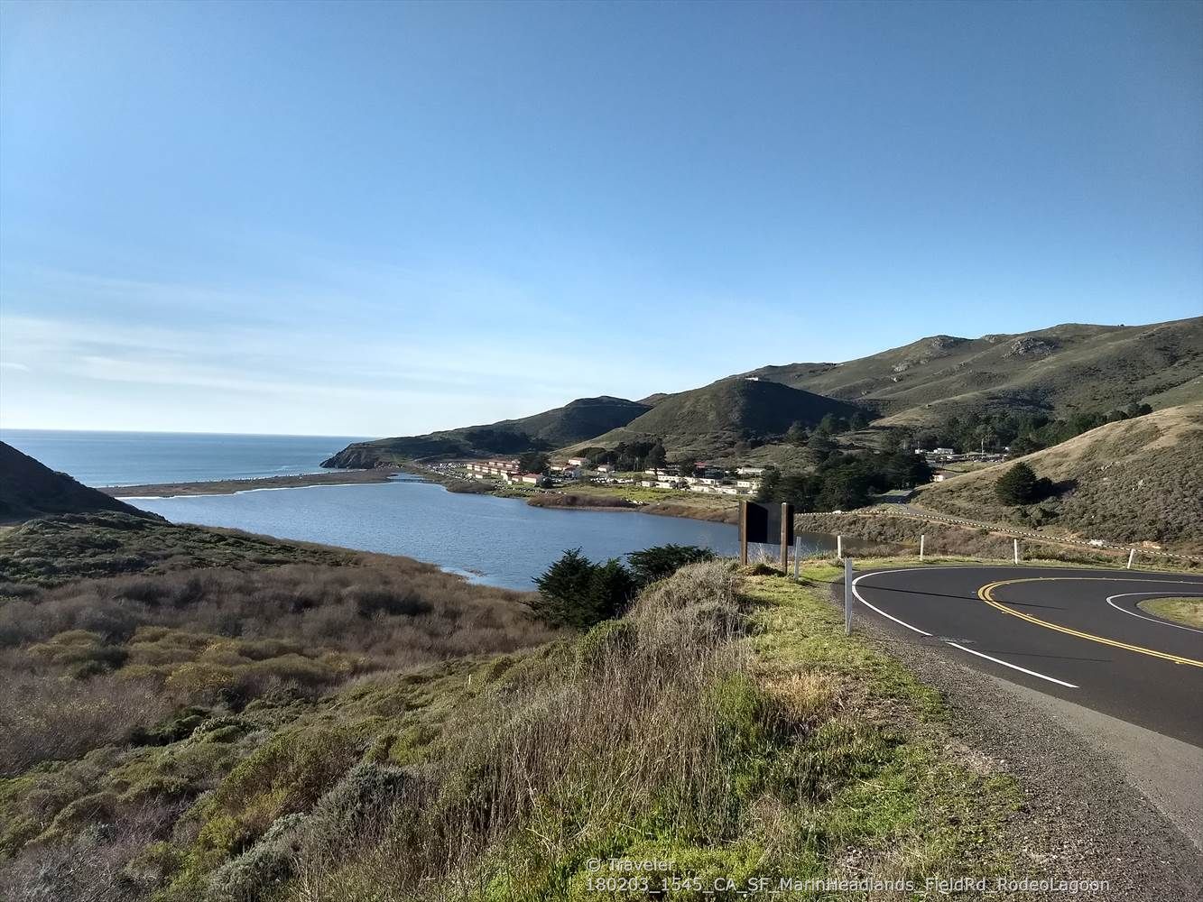 Winding road curves around a calm bay with a small town and green hills. - Baker-Barry Tunnel – Sausalito Waterfront loop from Sausalito