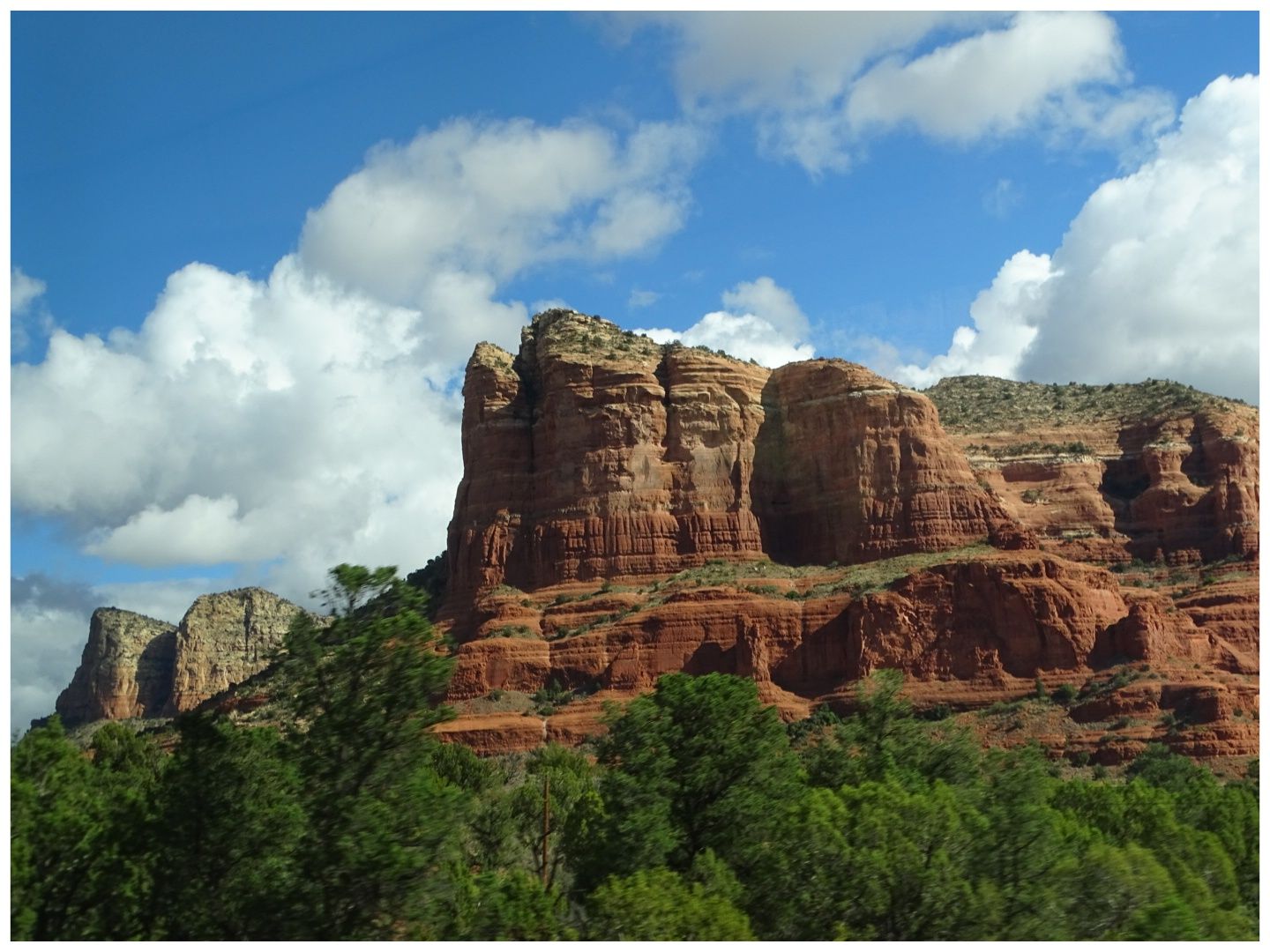 Majestic red rock cliffs towering over green trees under a cloudy blue sky. - Slim Shady and Made in the Shade Loop