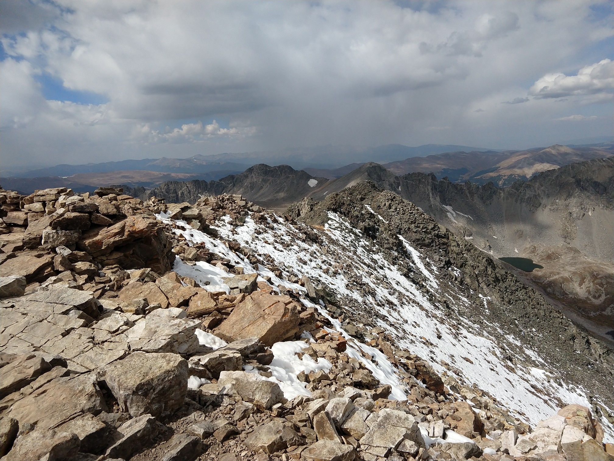 Rocky mountain ridge with patches of snow under a cloudy sky. - Quandary Peak Trail