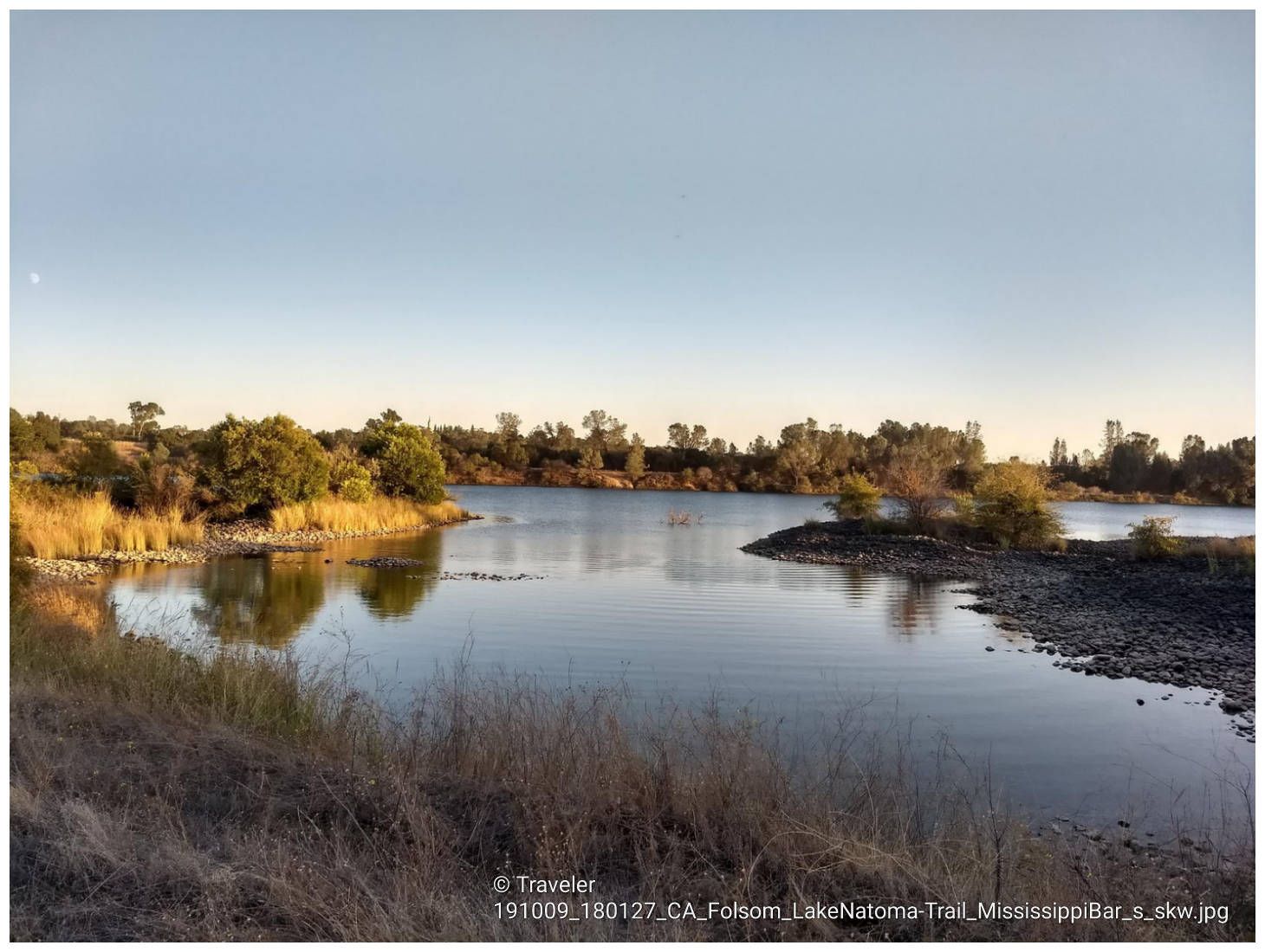 Calm river reflecting trees and sky, with grassy banks. - Folsom Lake State Recreation Area 5k running loop