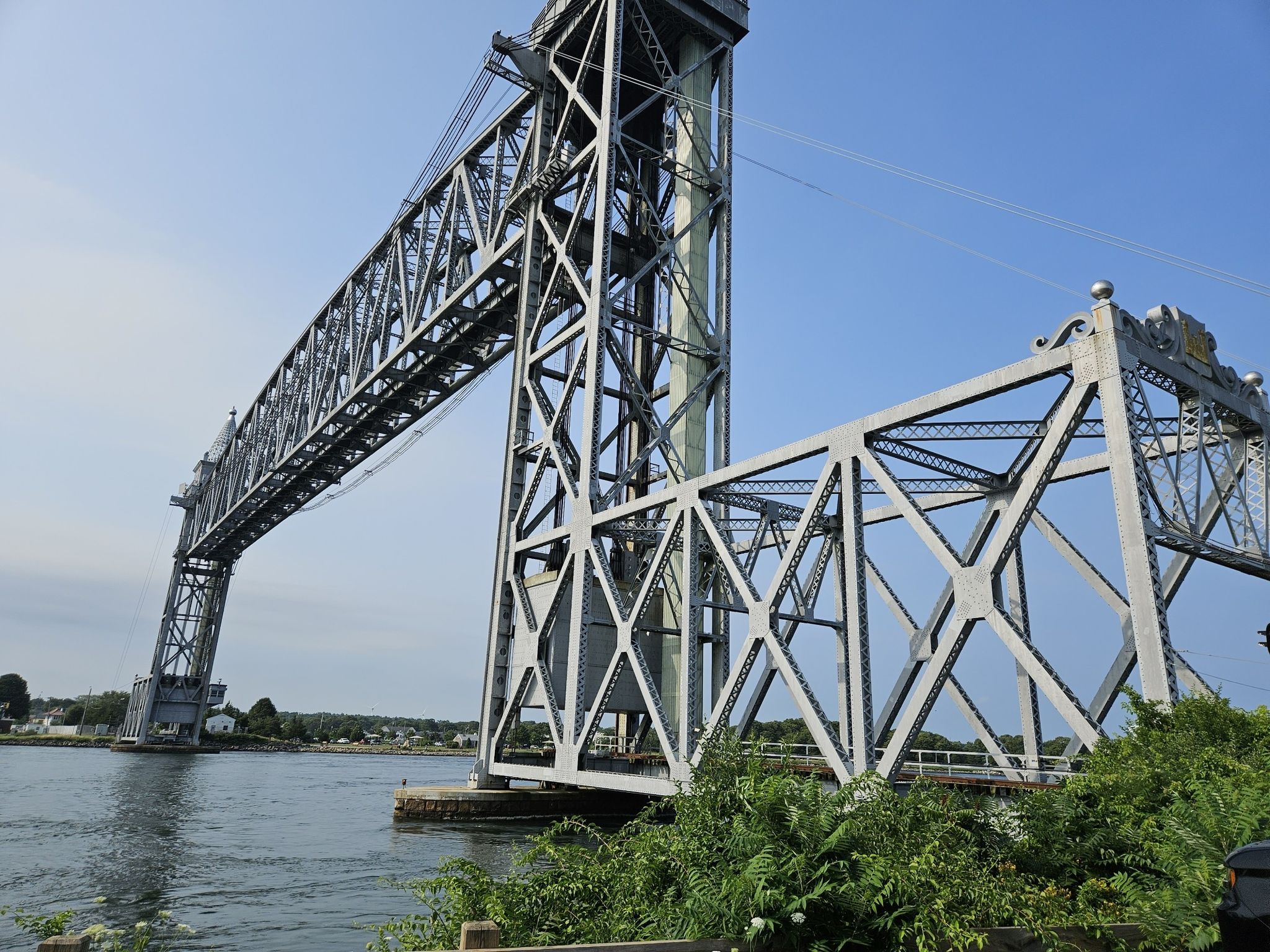 Close-up of a massive steel truss bridge structure over calm water. - Cape Cod Canal Bikeway