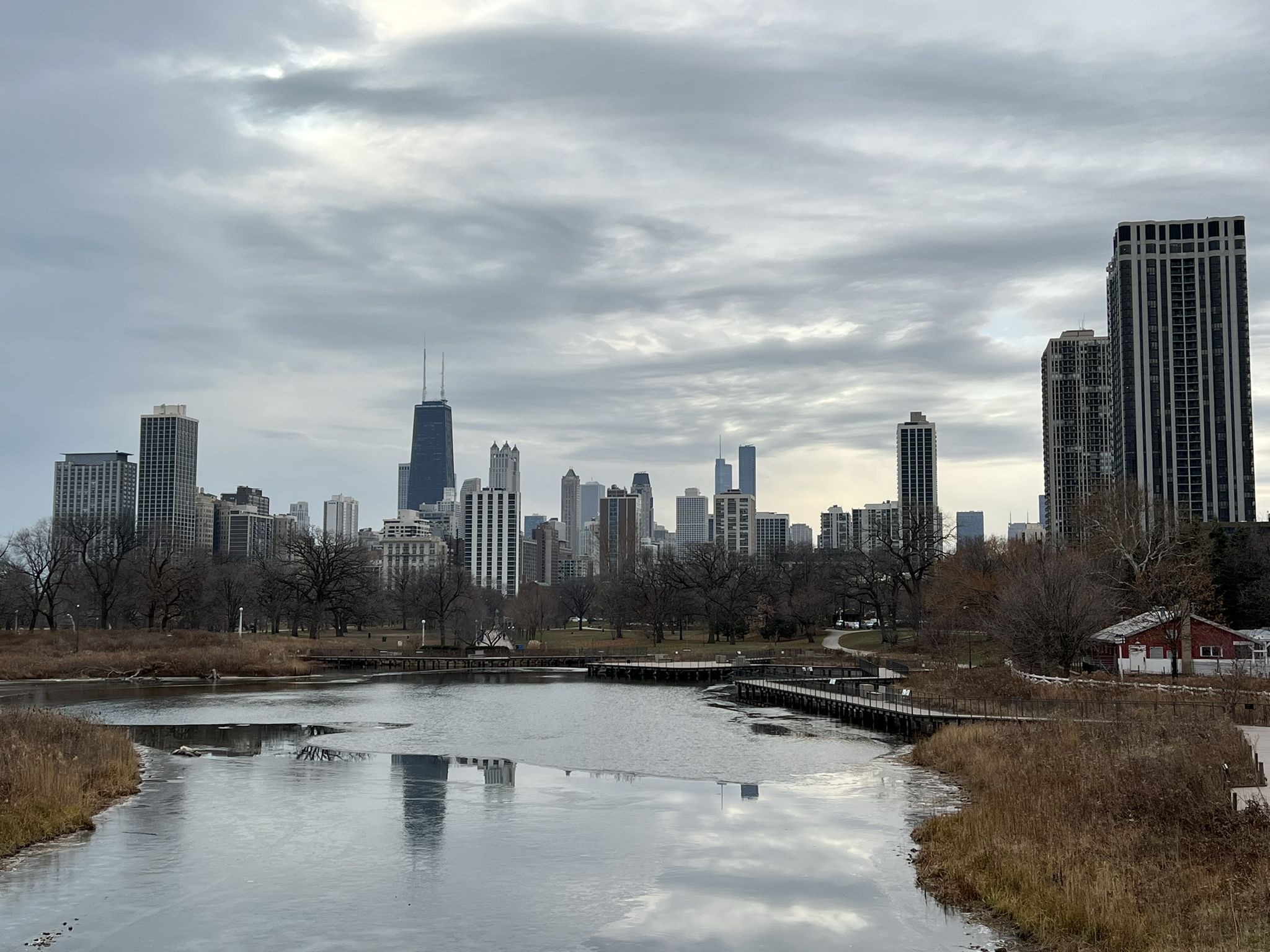 Icy river reflecting city skyline under cloudy sky, with bare trees. - Grand Illinois Trail: Chicago Lakefront to Wolf Lake
