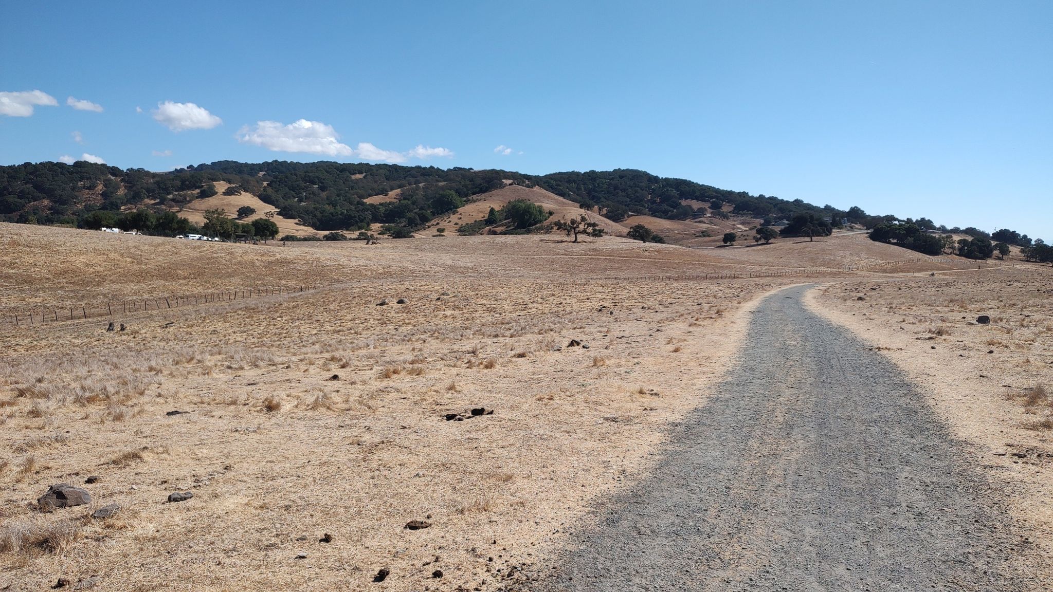 Gravel path through dry, golden fields leading to distant green hills. - Mendoza Trail loop from Mendoza Ranch Entrance