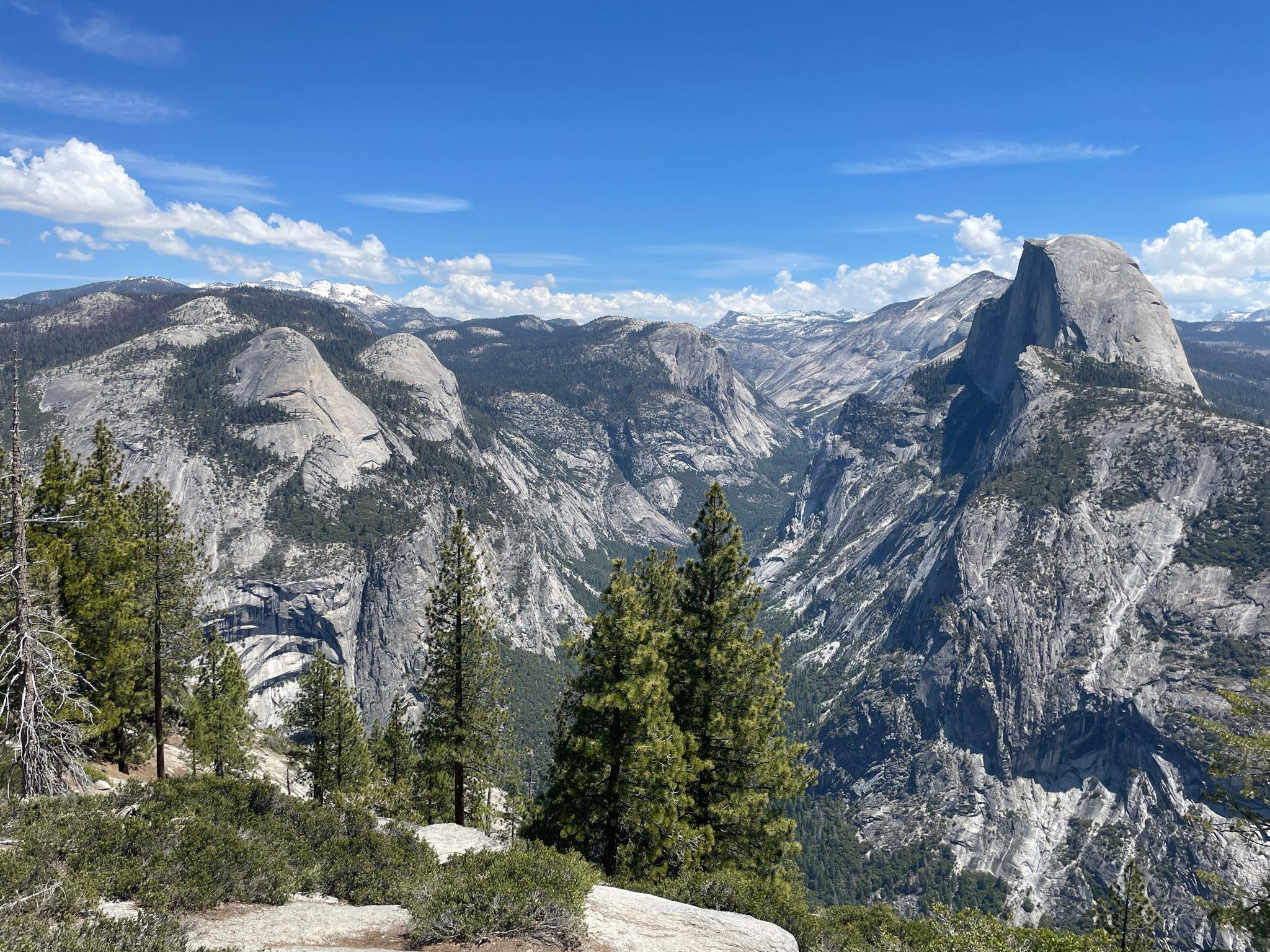 Panoramic view of a grand valley with granite peaks and green trees. - Glacier Point Trail