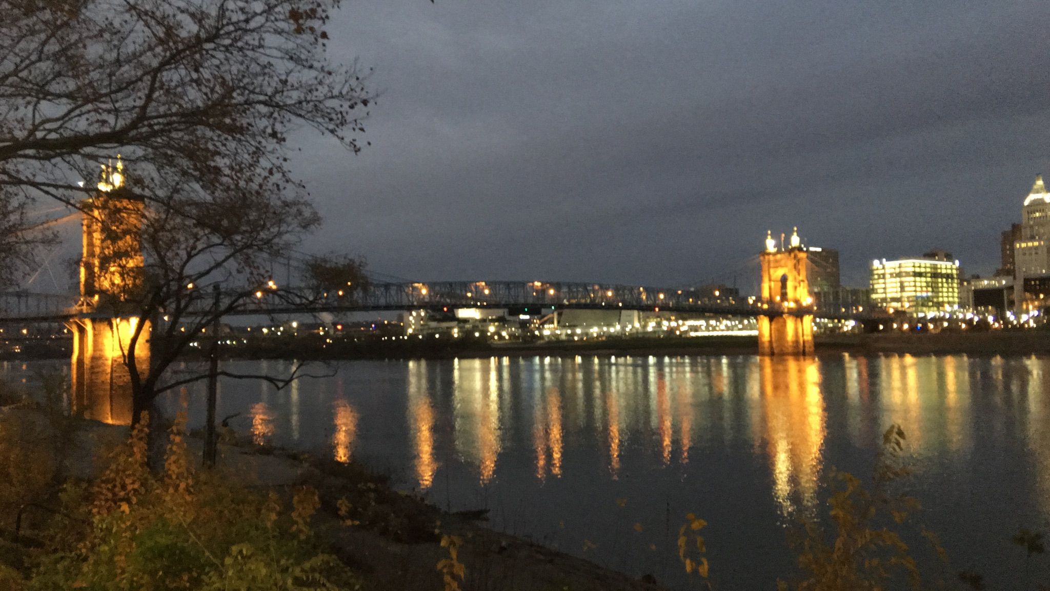 Illuminated bridge and city skyline reflect in the river at night. - Ohio River Trail