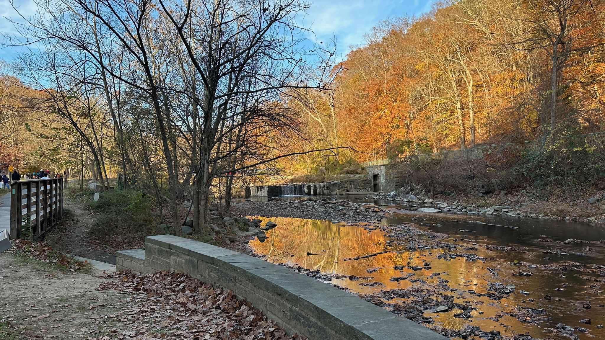 A river reflects vibrant autumn trees under a bright, clear sky. - Western Ridge and Valley Trail Loop
