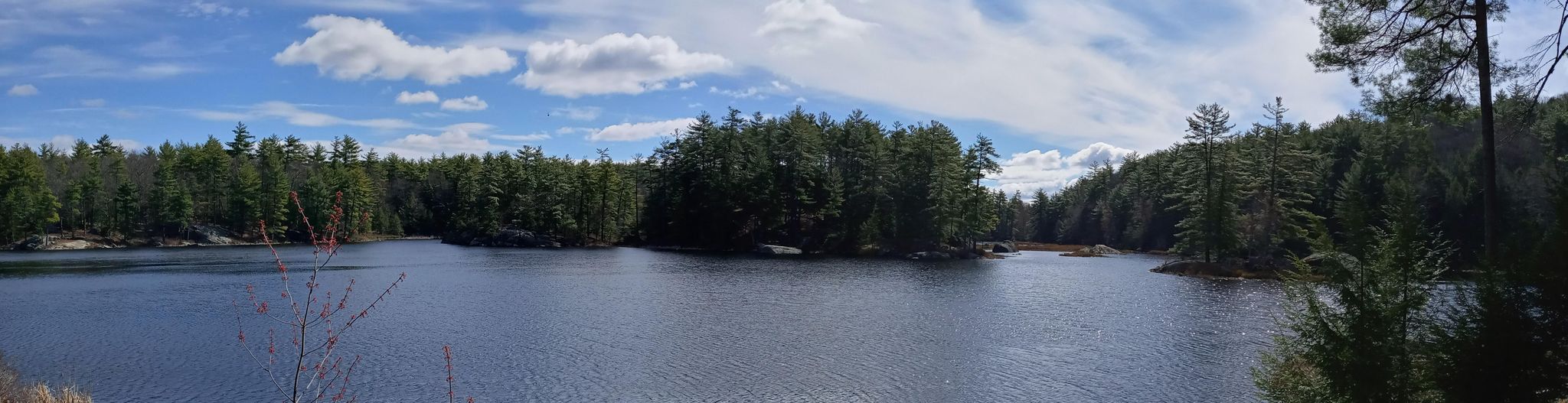 Wide panoramic view of a calm lake surrounded by dense evergreen forests. - Round Pond, North Mountain and Shaw Trail Loop