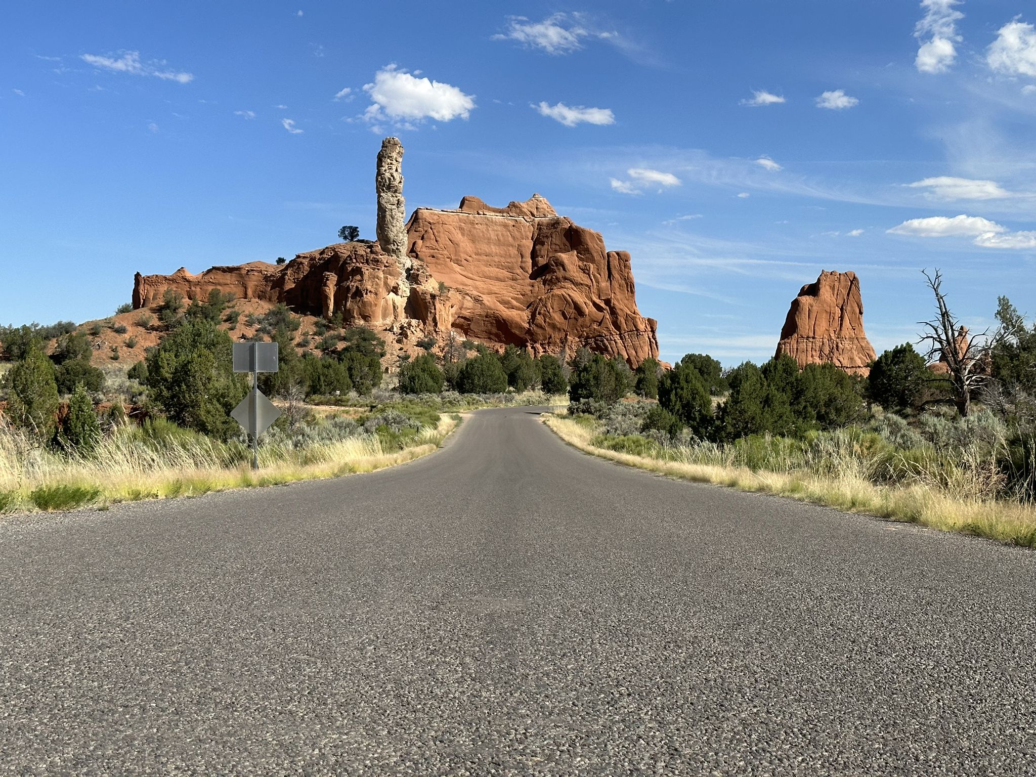 Paved road leading towards a tall rock spire and red rock formations. - Kodachrome Basin State Park loop from Kodachrome Basin State Park