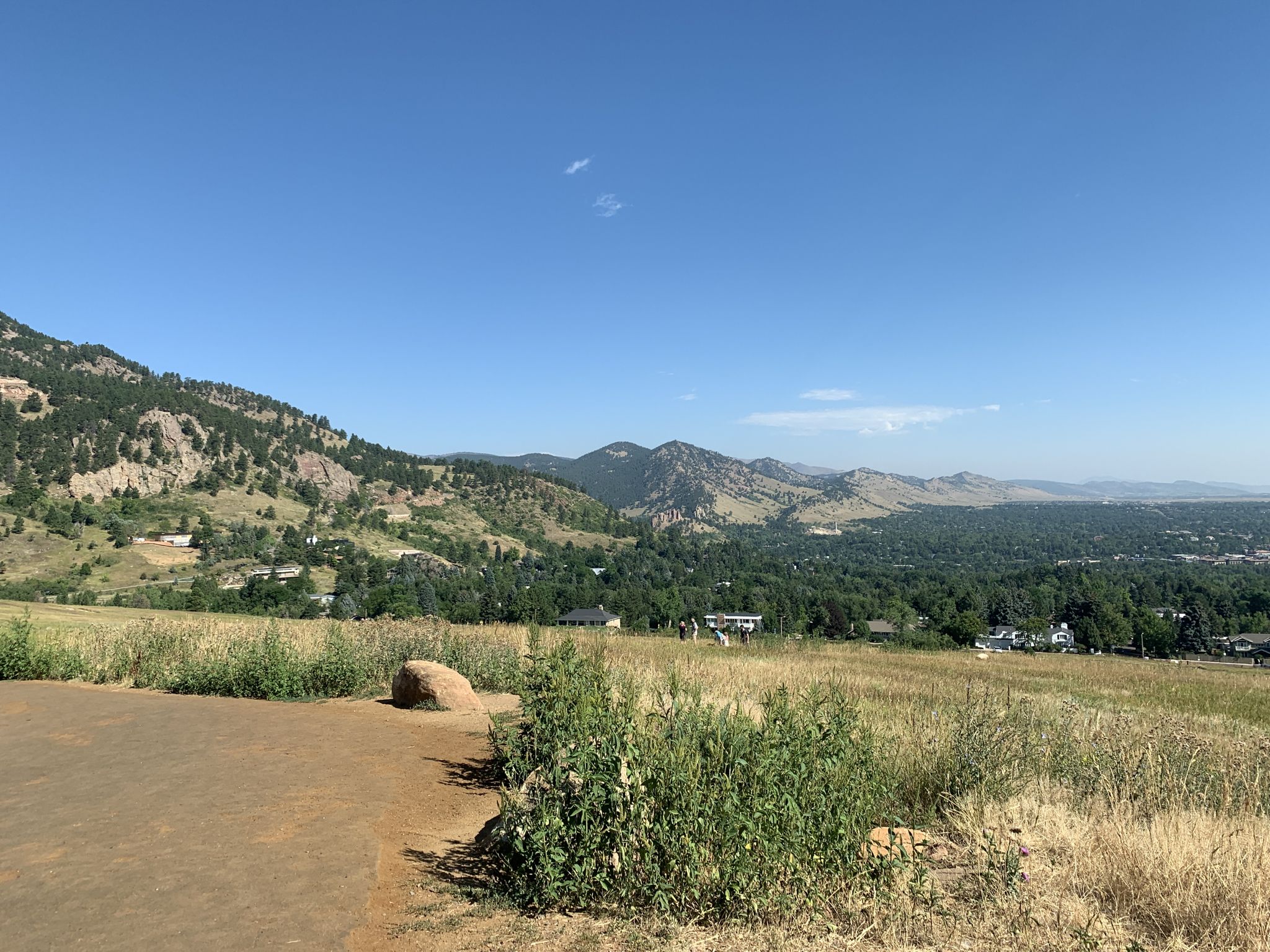 Grassy field with distant mountains and a city under a clear blue sky. - Enchanted Mesa, Bluebell Spur, and Chautauqua Loop