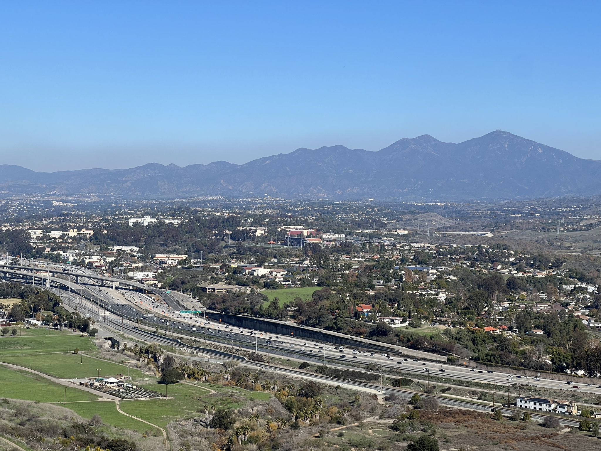 Expansive view of a city, highway, and distant mountains under a clear sky. - Colinas Ridge and Shea Trail Loop