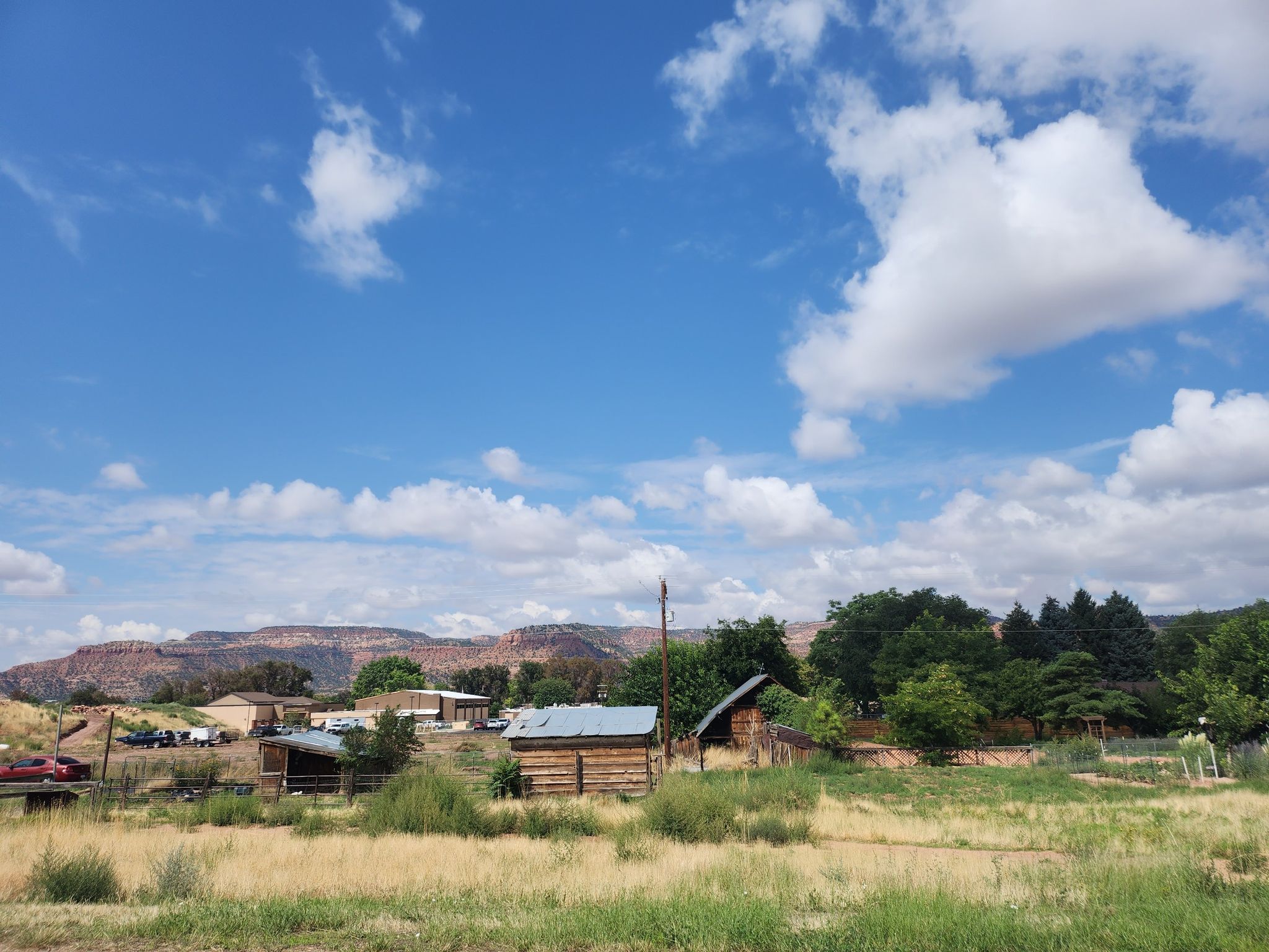 Rural scene with small buildings, green fields, and distant red mountains. - K-Hill – K-Hill Trail loop from Kanab