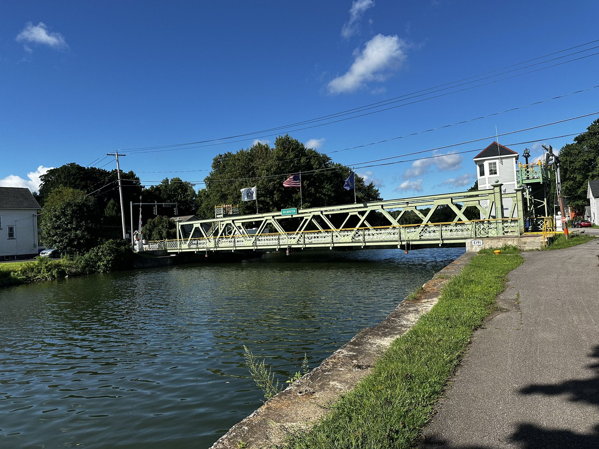 A green truss bridge spans a canal on a clear, sunny day. - Holley Lift Bridge loop from Village of Brockport