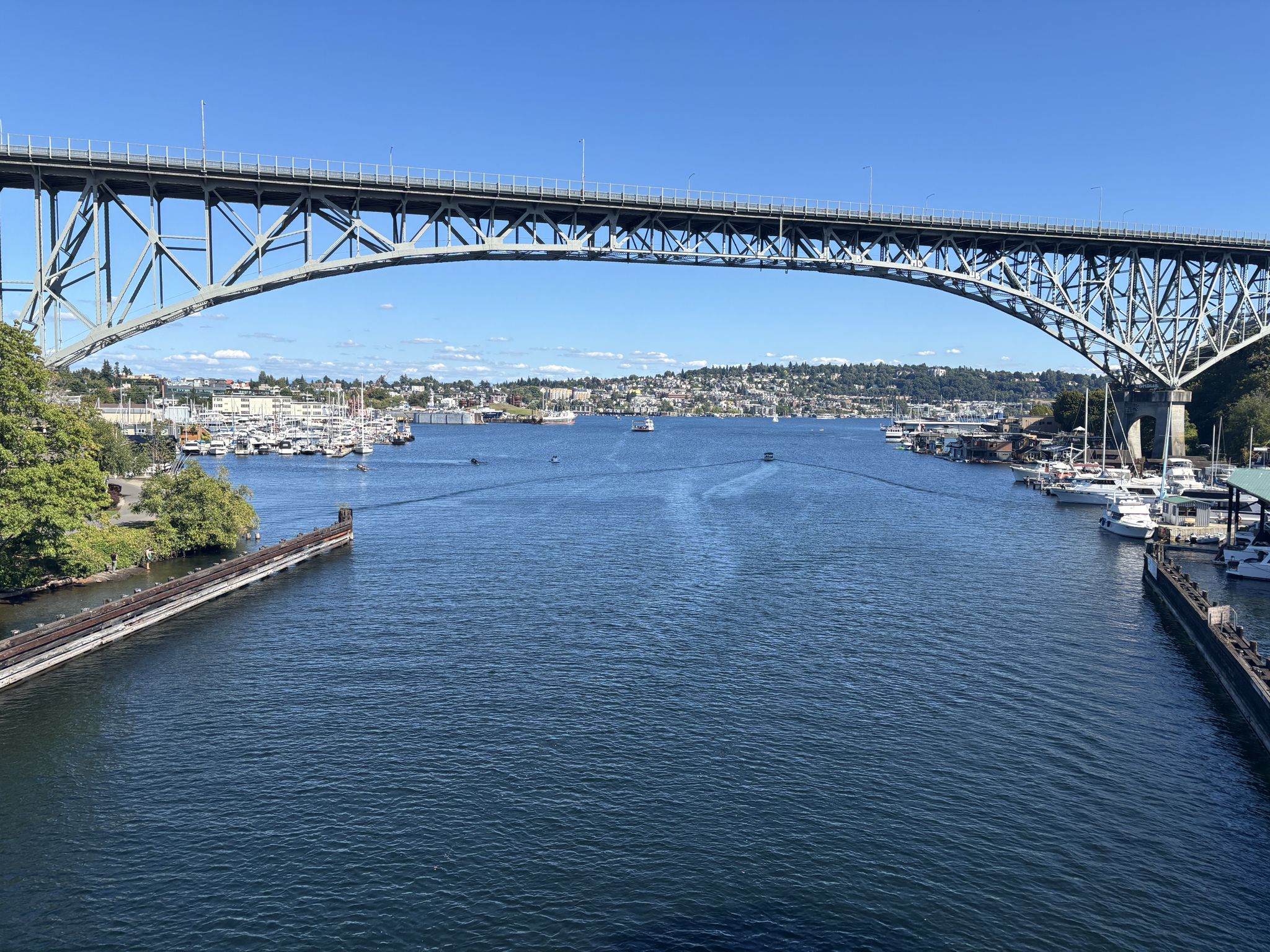 A large steel arch bridge spans a wide waterway with boats, under a clear sky. - Fremont Bridge – Fremont Bridge loop from The Walrus and the Carpenter