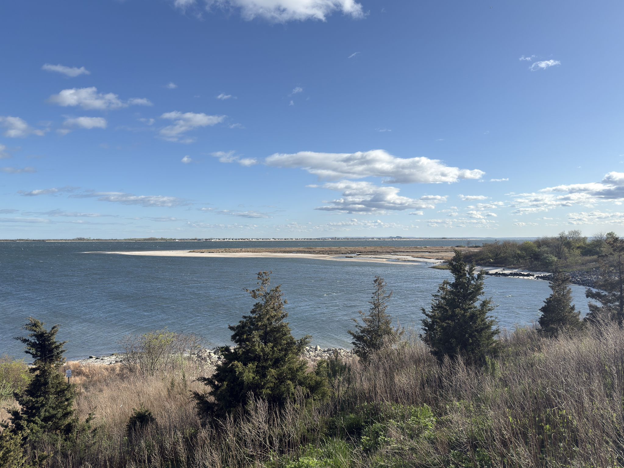 Bay with sandy spit, green trees, and blue sky with clouds. - Jamaica Bay Greenway Loop