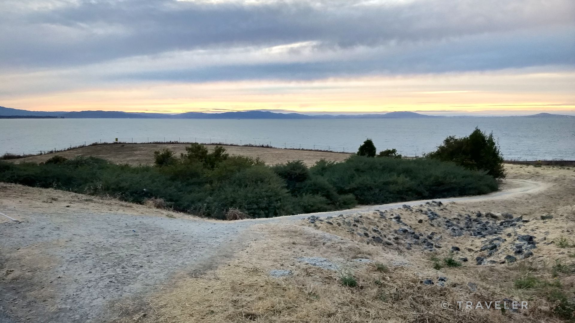Dirt path overlooking a vast body of water under an overcast sky. - San Francisco Bay Trail
