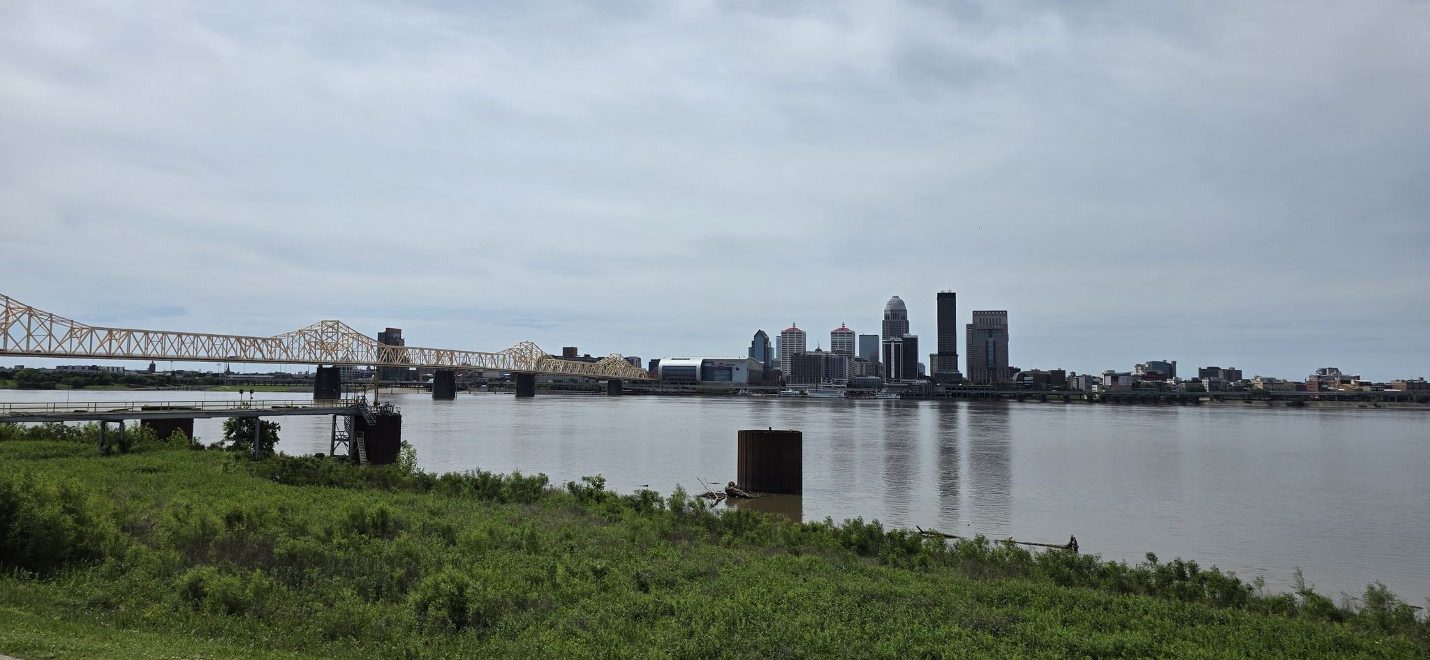 City skyline and a large bridge across a wide river under an overcast sky. - Falls of the Ohio State Park loop from New Albany