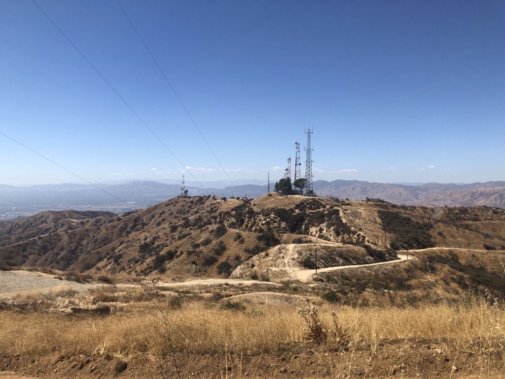 Communication towers on a dry, rocky hilltop under a bright blue sky. - Verdugo Peak loop from Downtown Burbank