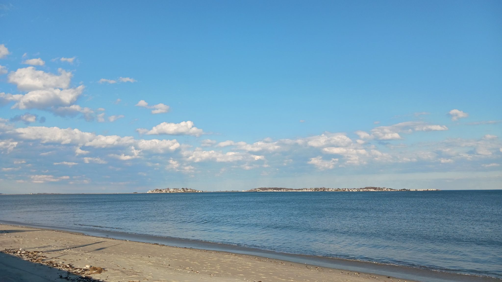 Calm ocean meets sandy beach under a partly cloudy blue sky. - Revere Beach loop from Nahant