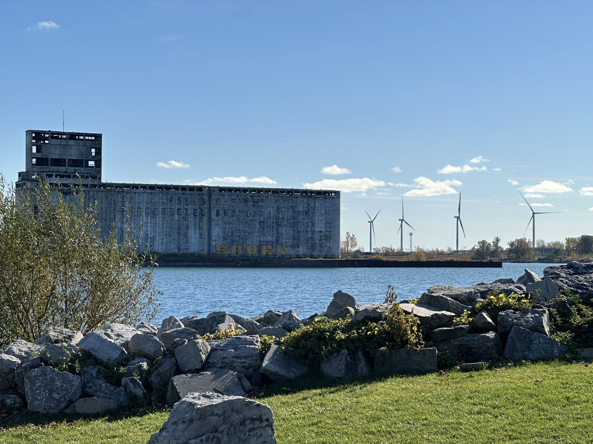 Large industrial building by water, wind turbines, and rocky foreground. - Tiff Nature preserve to Reinstein Woods Nature Preserve And Environmental Education Center loop
