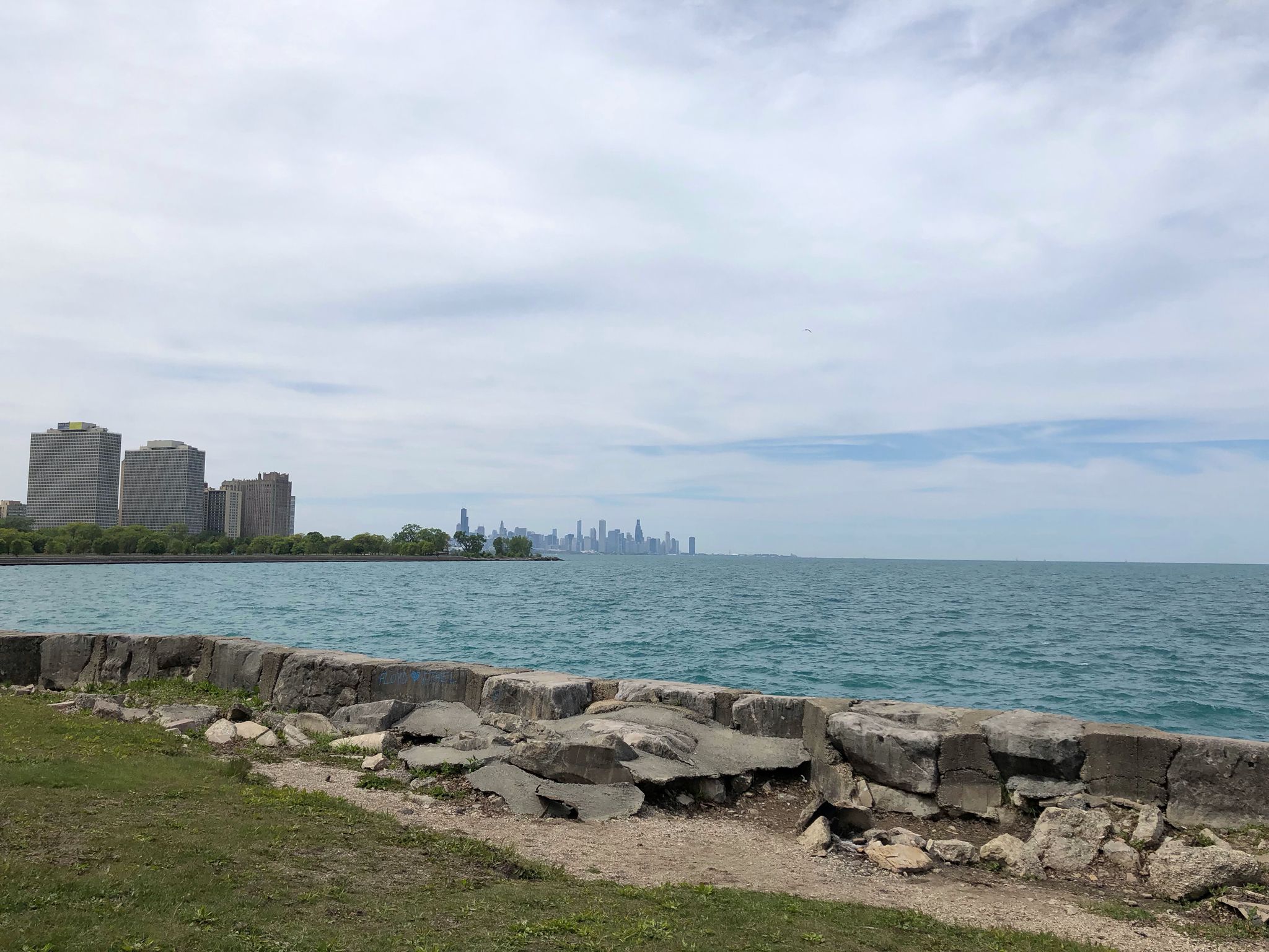 Distant city skyline across a large lake under an overcast sky. - Hyde Park – Model Yacht Basin loop from The University of Chicago