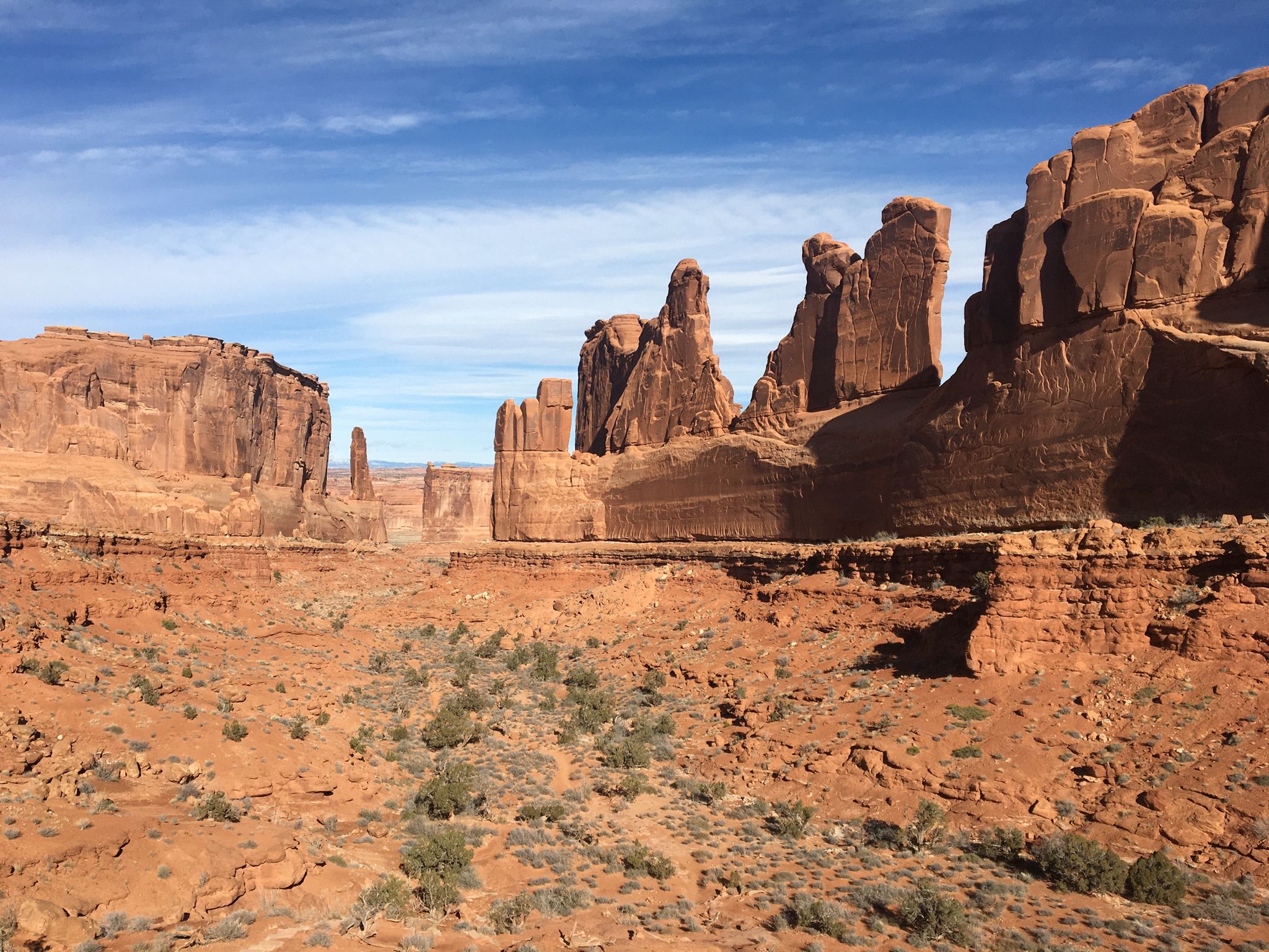 Red rock formations and desert landscape under a blue sky with clouds. - Park Avenue Trail