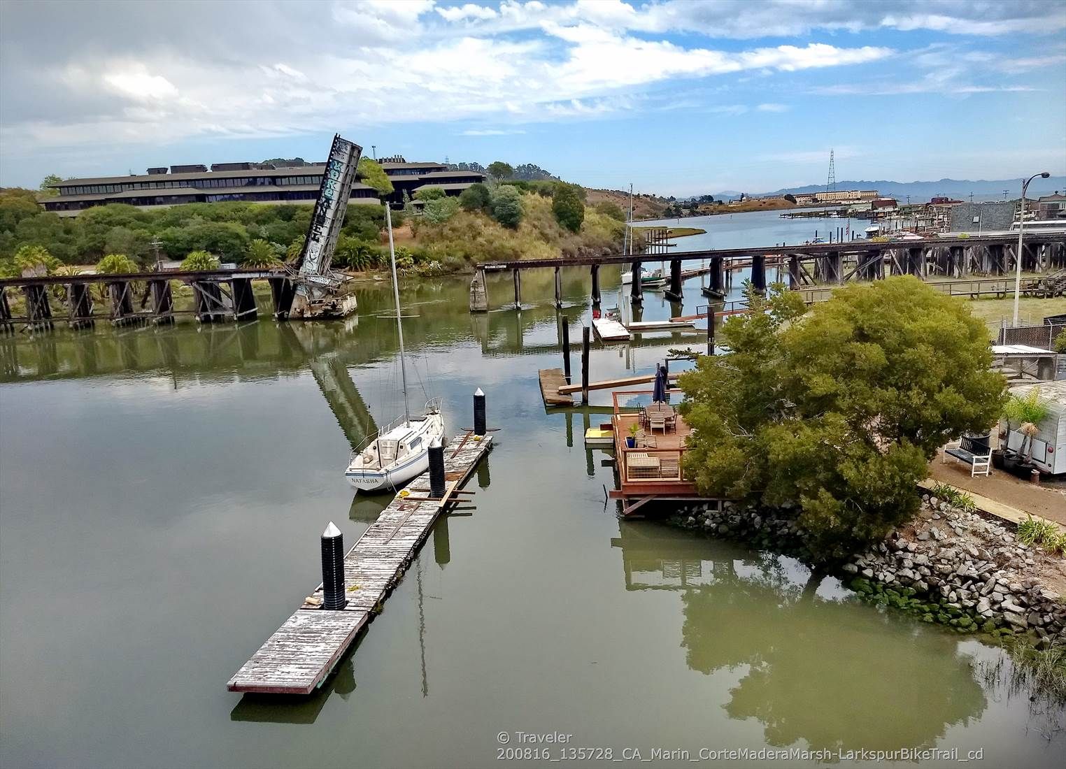 Boats docked in a calm river with a raised drawbridge under a cloudy sky. - Marin Headlands and Bay Trail Loop