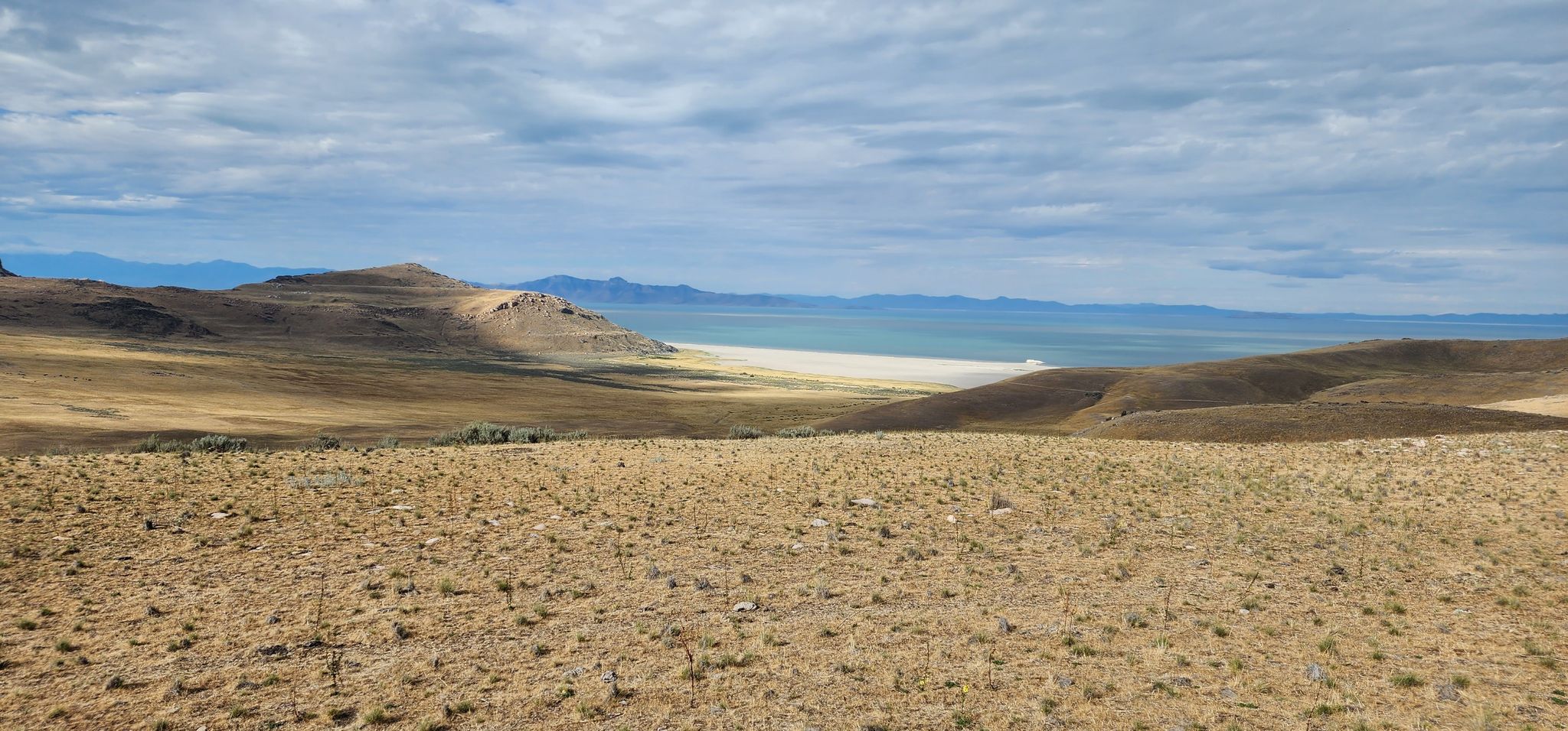 Expansive dry, grassy landscape with a large body of water under a cloudy sky. - Antelope Island State Park – Antelope Island views loop from Buffalo Point