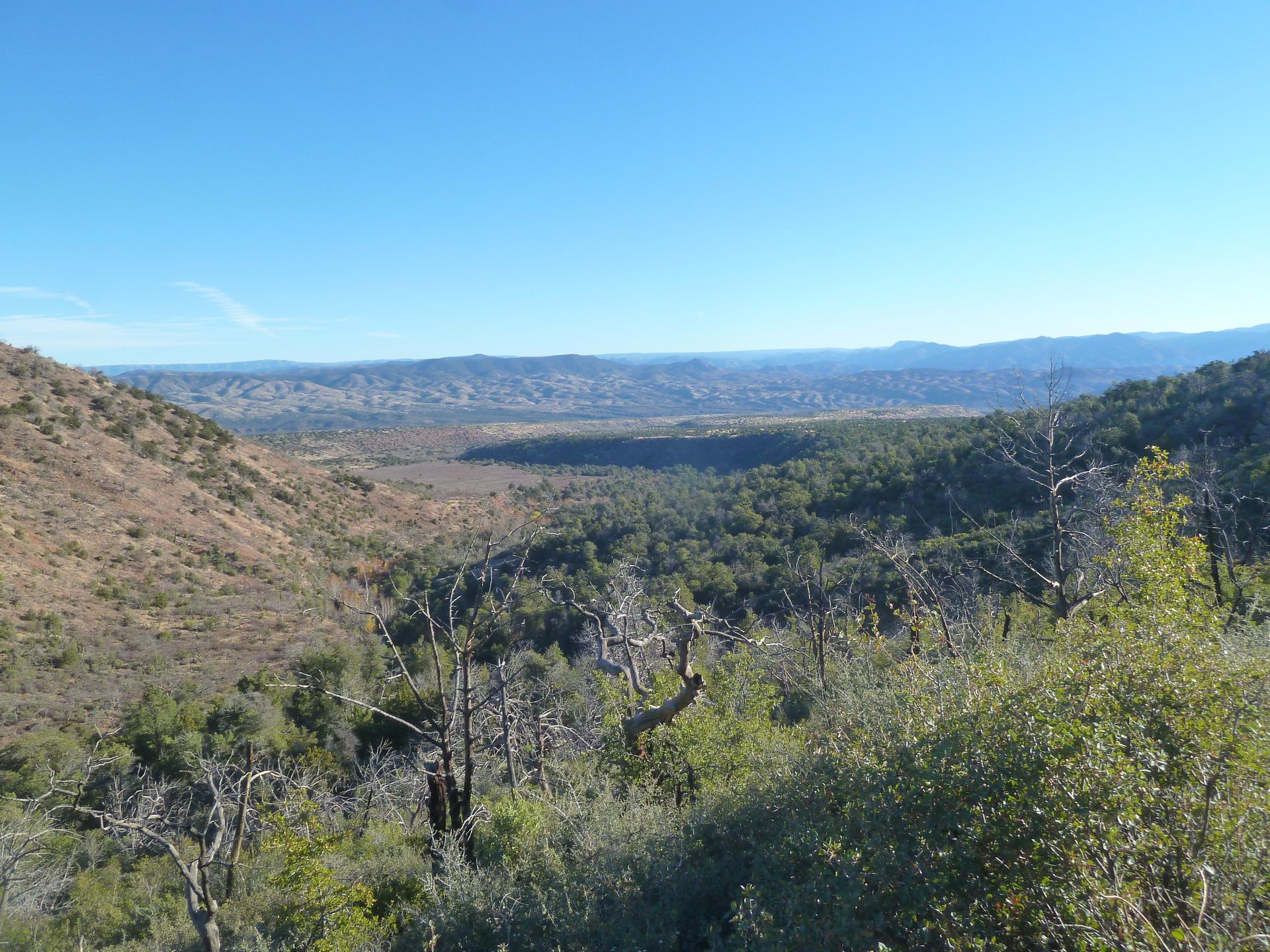 Expansive view of a dry valley with scrubby hills under a clear blue sky. - Barnhardt Trail Waterfall