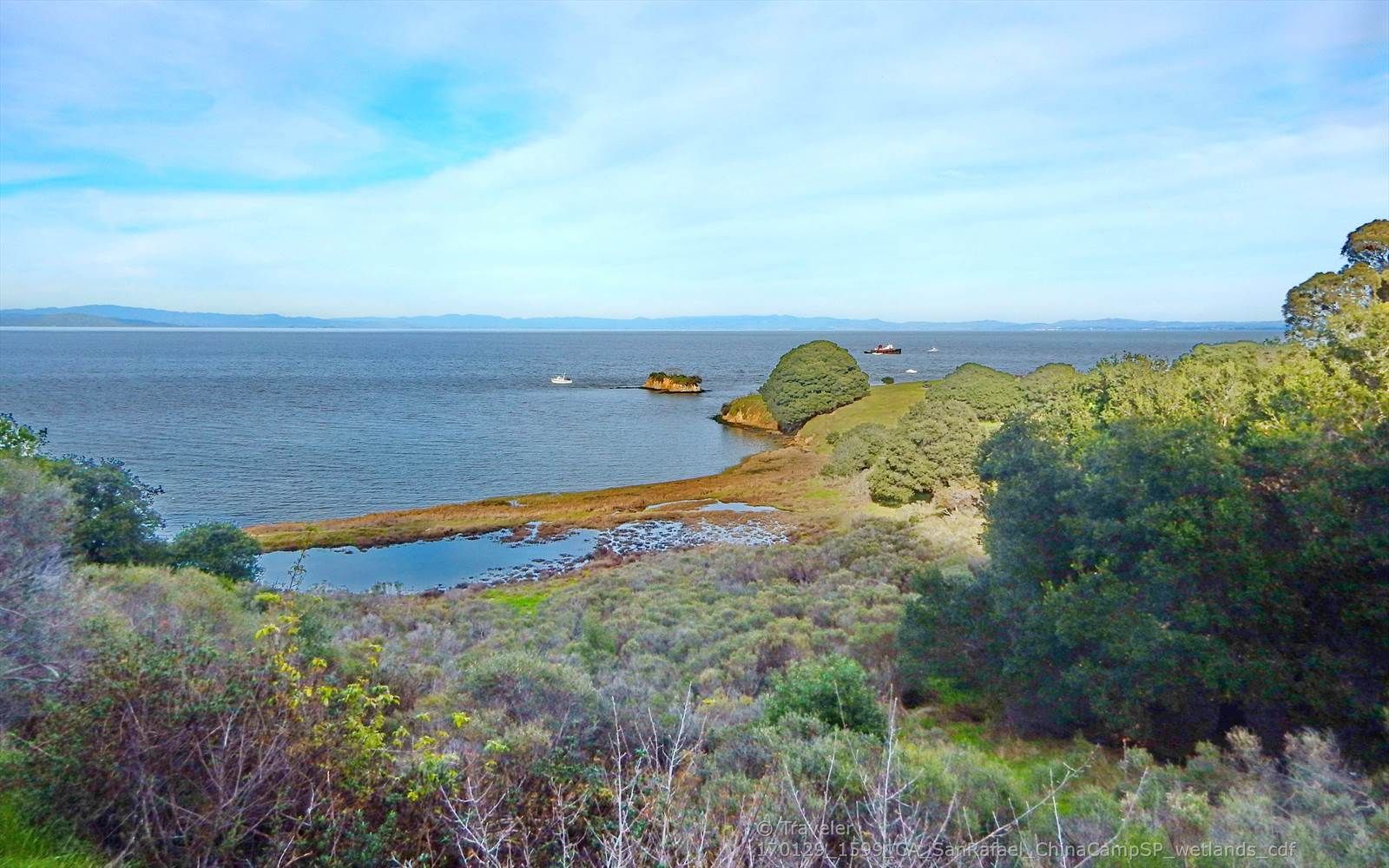 Wide view of a bay with green hills, small islands, and boats. - Shoreline and Bay View Loop