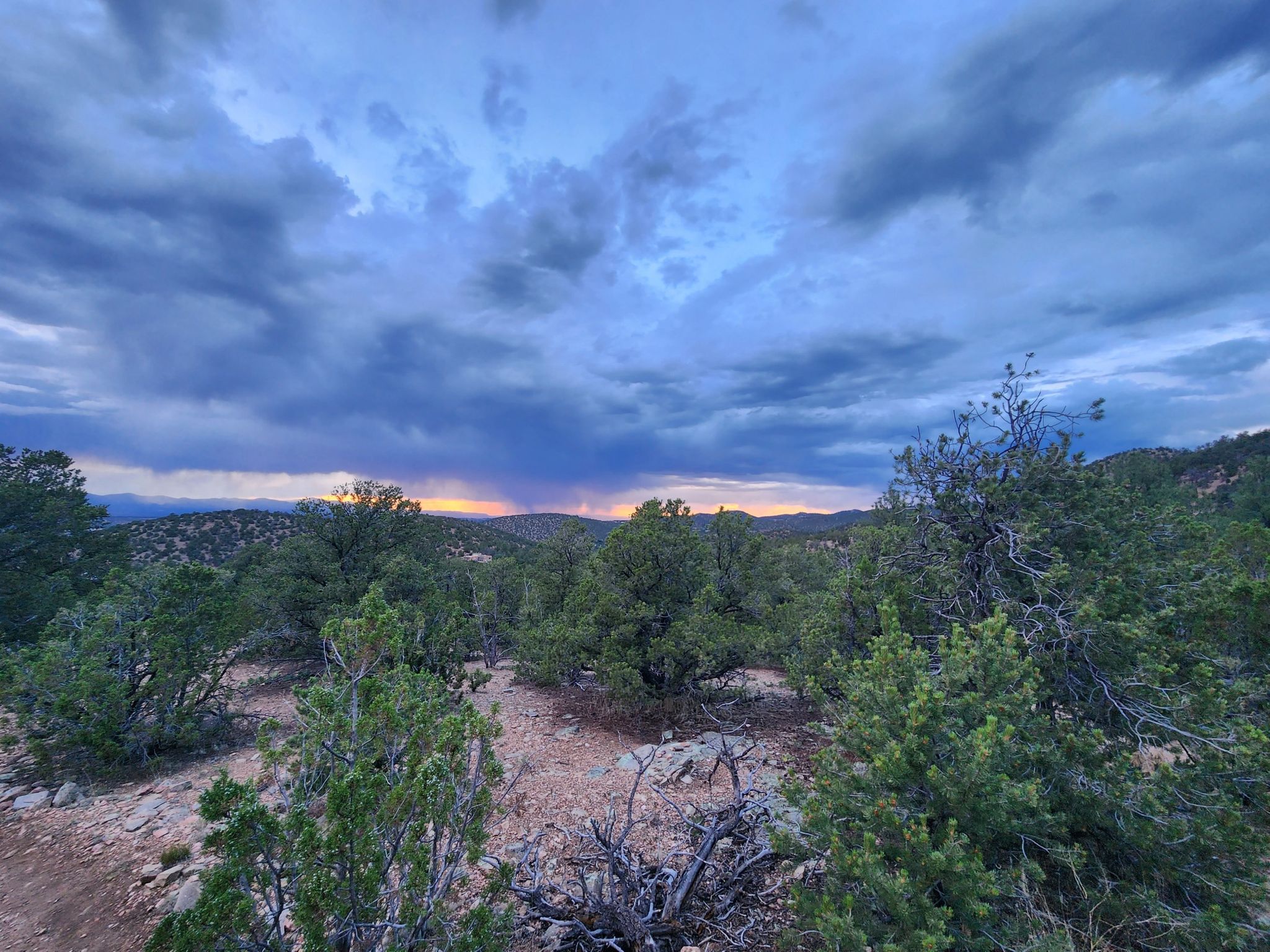 Forested landscape under a dramatic cloudy sky with a colorful sunset. - Atalaya Mountain via Atalaya Trail and Dale Ball Trails Loop