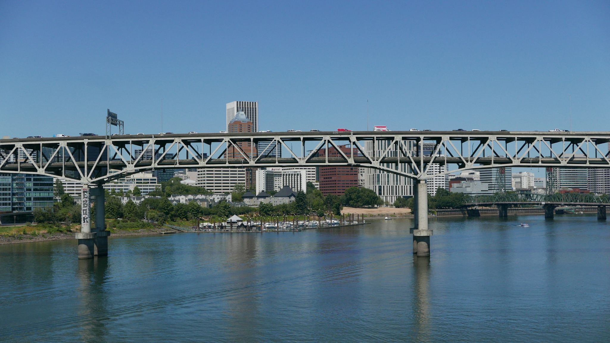 Large metal truss bridge spans a river with a city skyline beyond. - Tilikum Crossing loop from Rose VL Deli