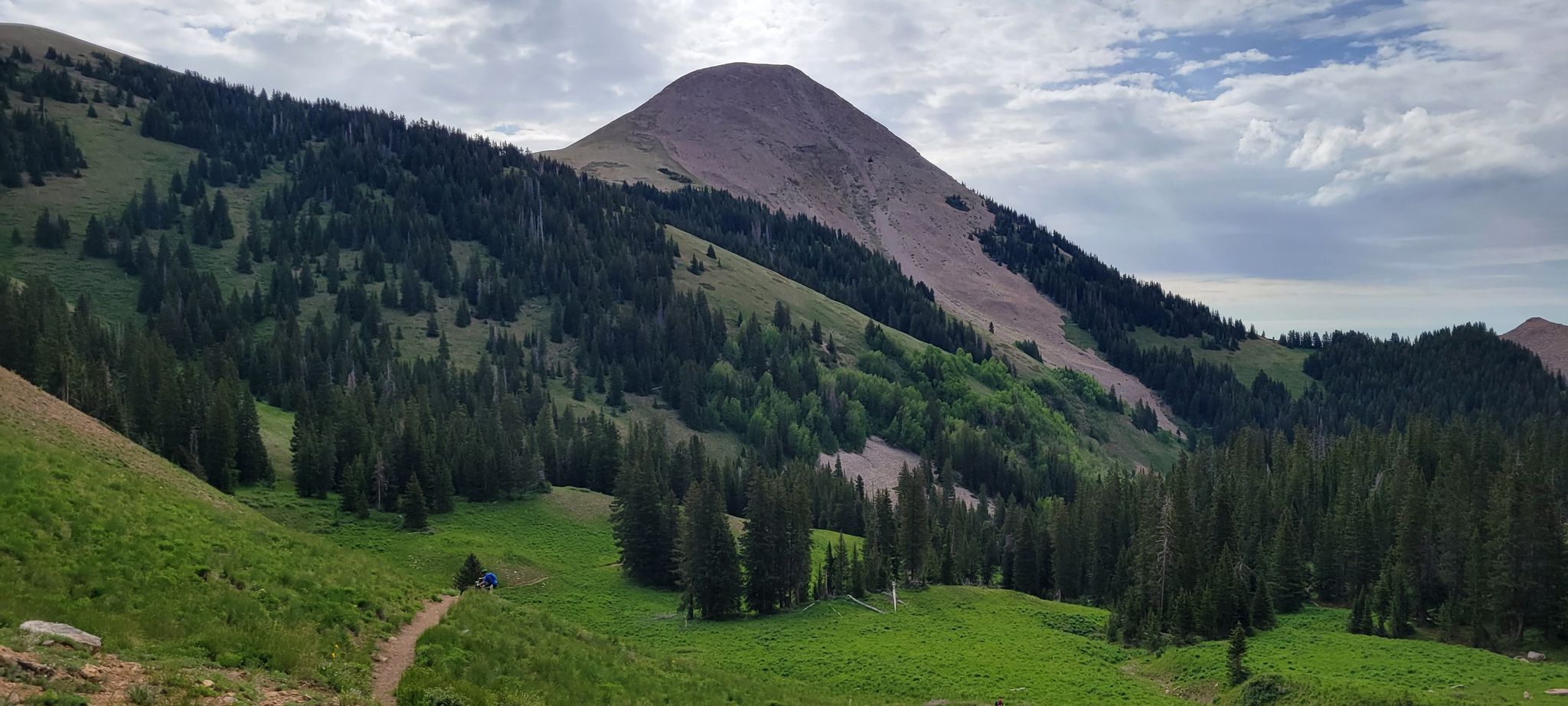Lush green mountain valley with a prominent peak under a cloudy sky. - Lake Oowah – Climb to Burro Pass loop from Lake Oowah Dam