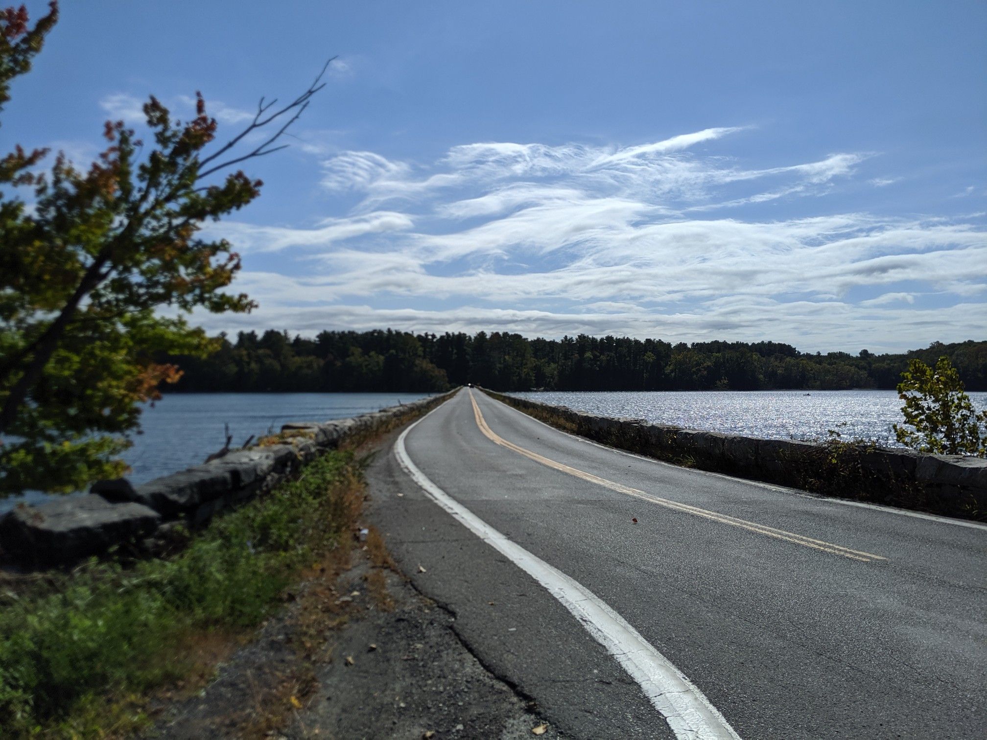 Road extends over a lake with forested shores under a cloudy sky. - Stockholm Hill – Boyd Corners Outlet Unit loop from Nimham Mount