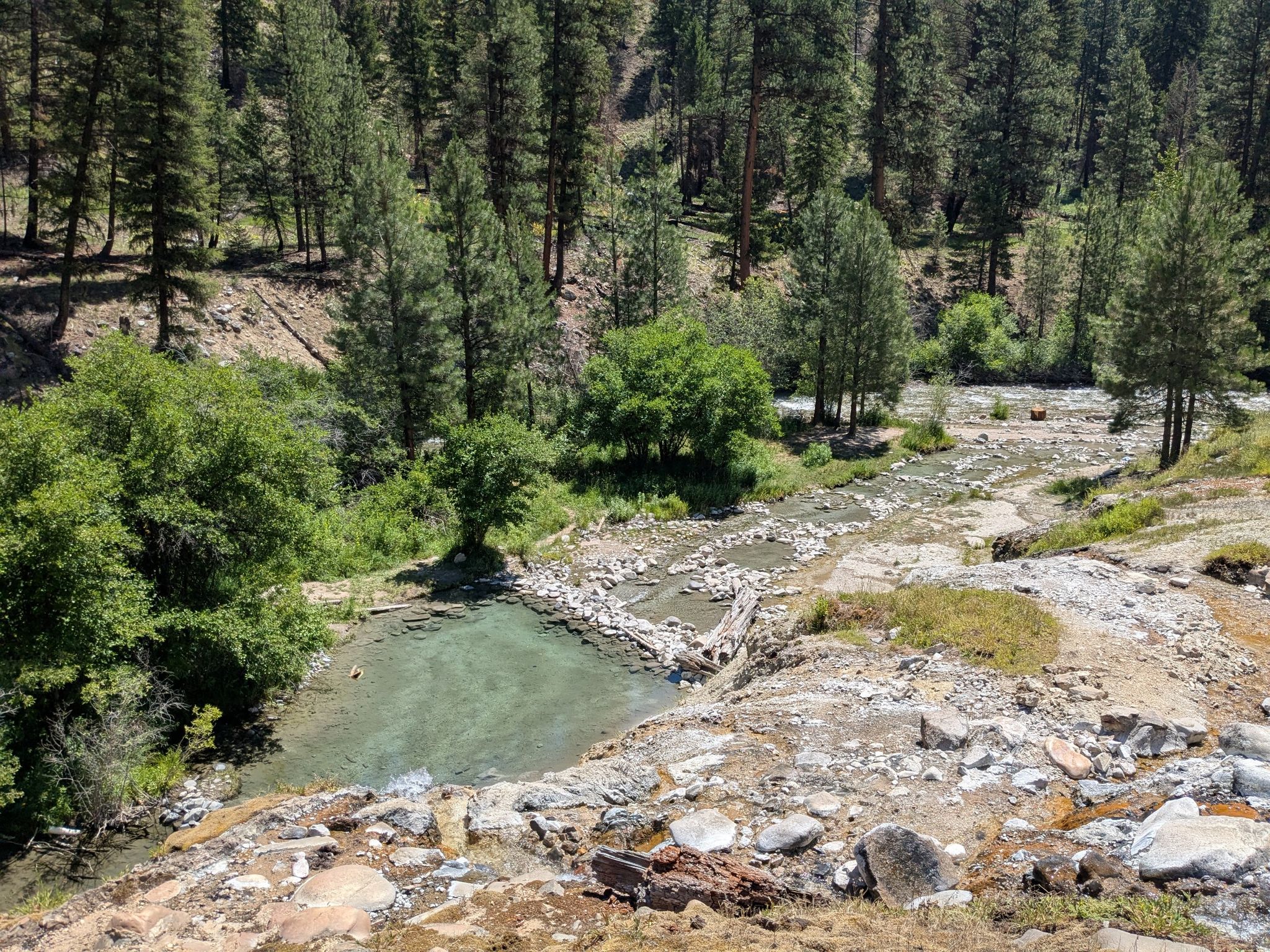 Sunny view of clear hot springs pools beside a rocky river in a forest. - Bonneville Campground – Bonneville Hot Springs loop from Warm Springs Trailhead (Airstrip)