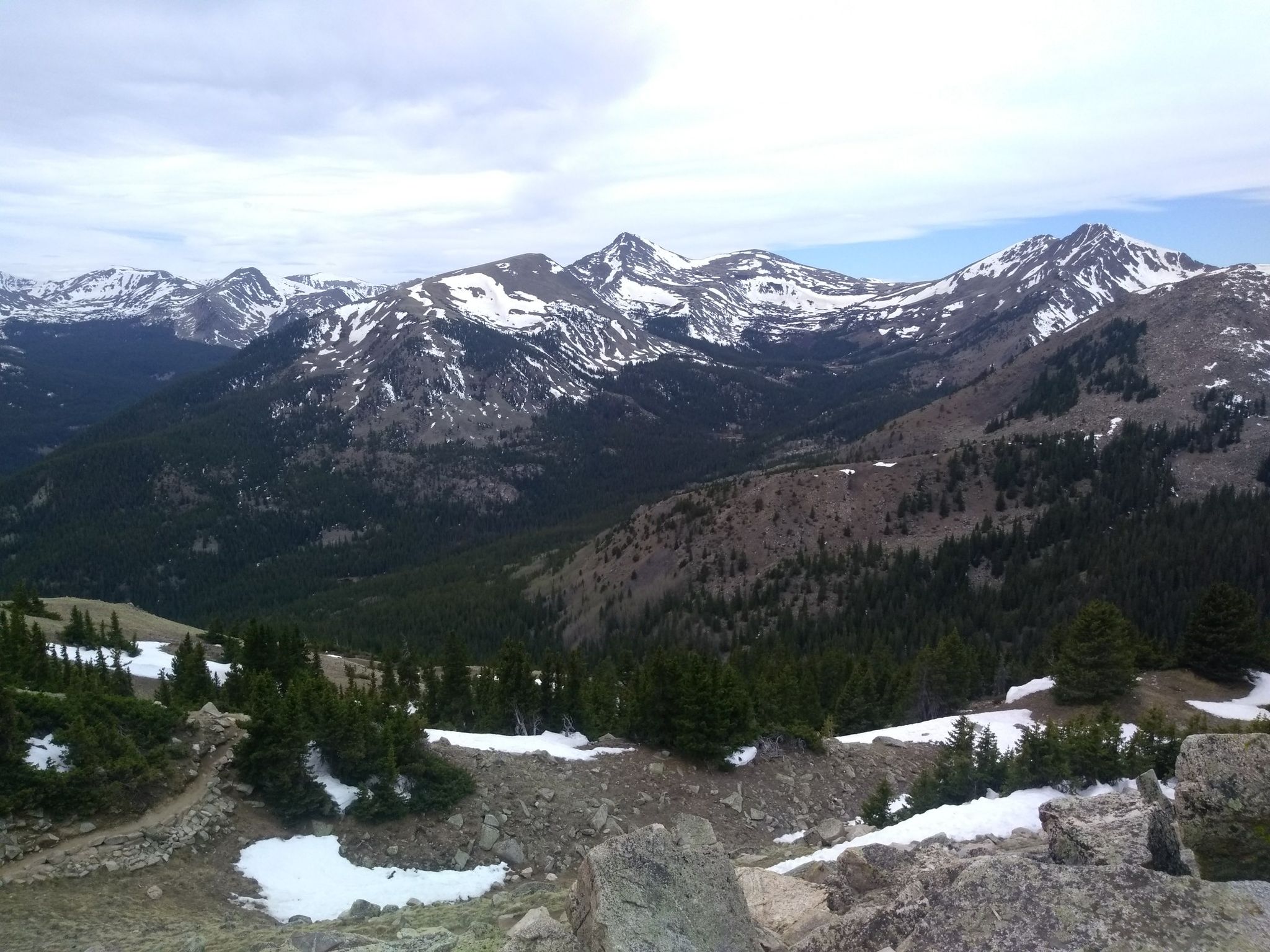 Snow-capped mountains and evergreen forests under a cloudy sky. - Mount Yale Trail