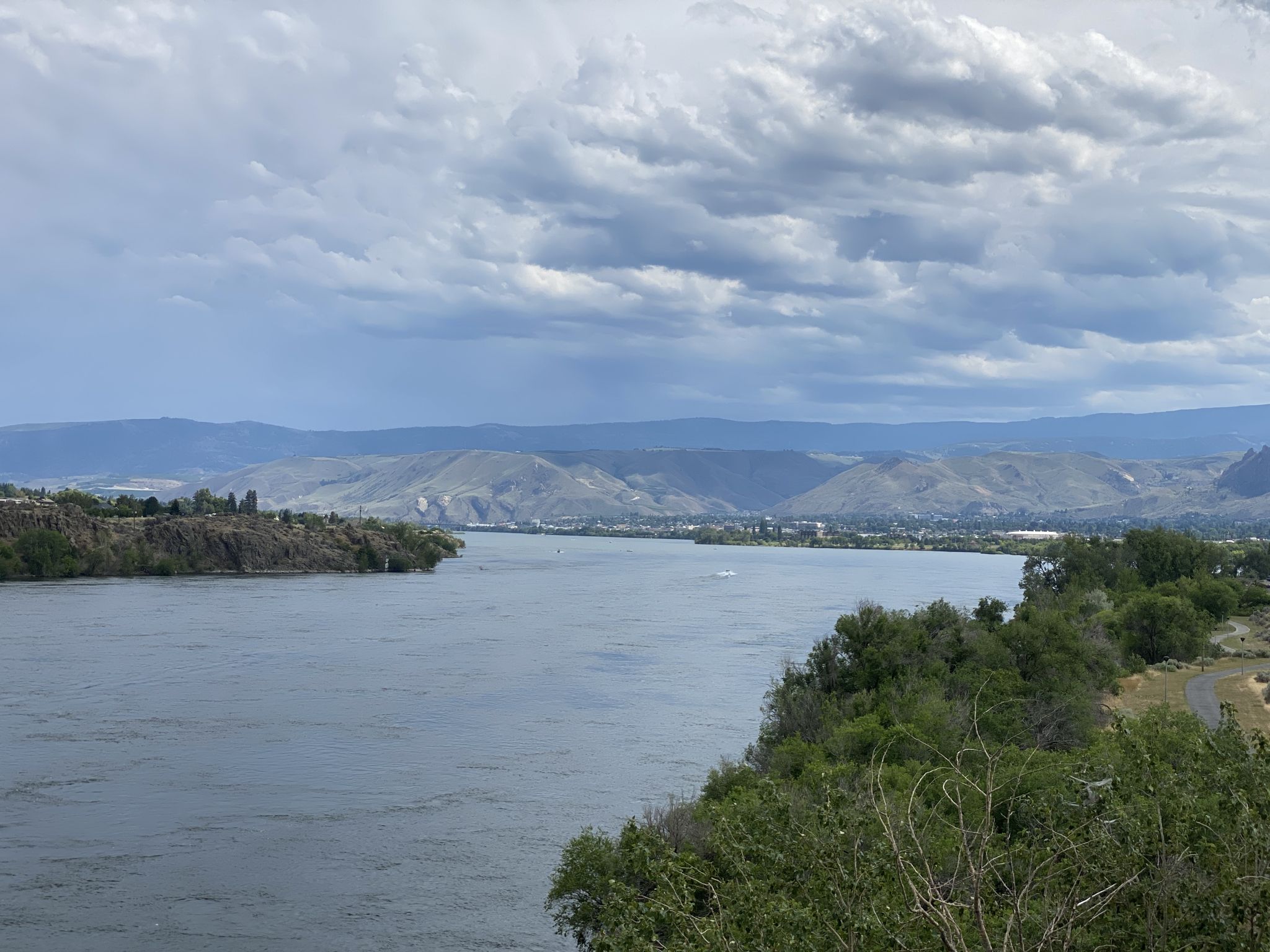 Wide river with forested banks, distant mountains under a cloudy sky. - Apple Capital Recreation Loop Trail