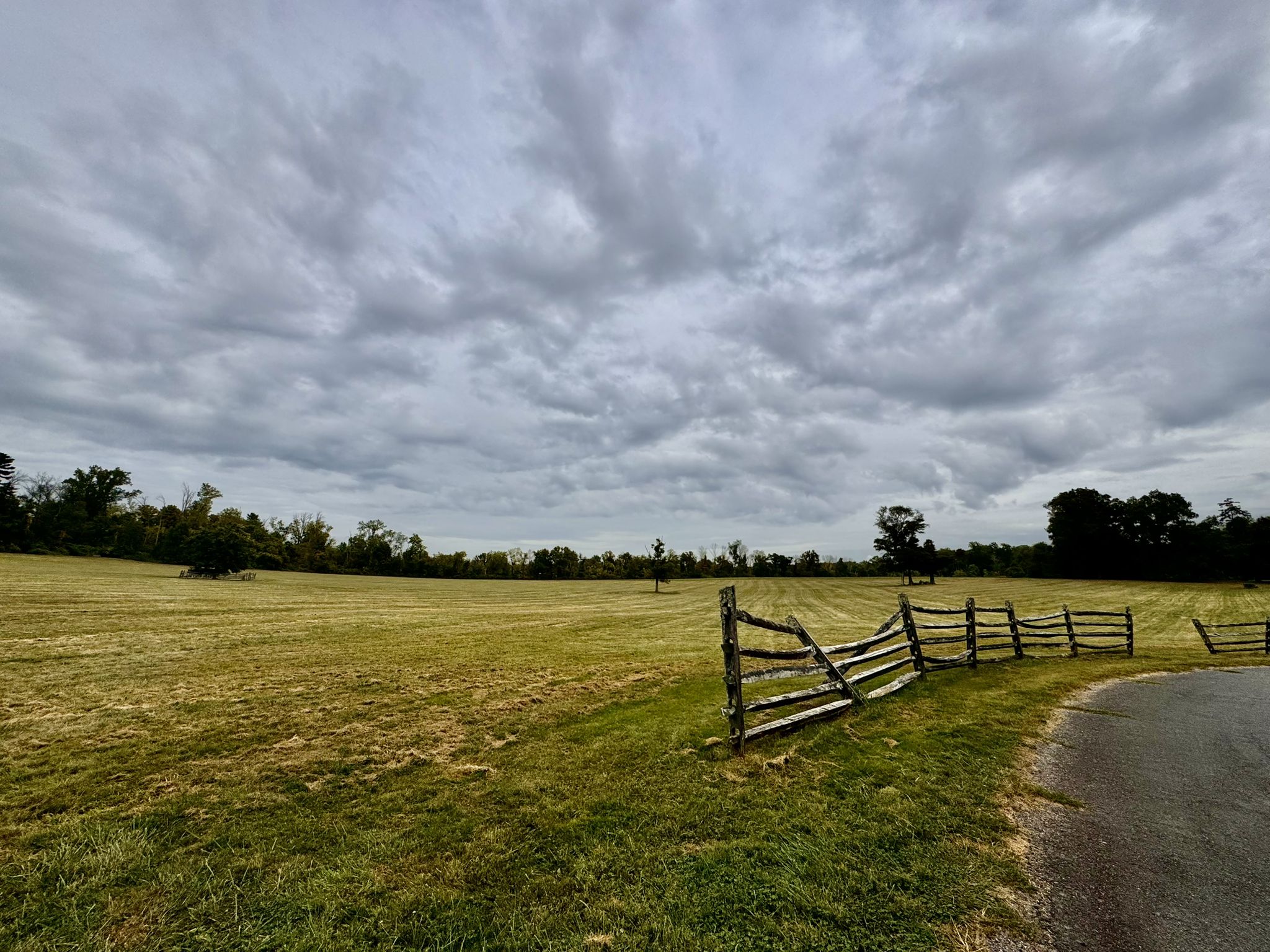 An open field with a wooden fence under a cloudy, overcast sky. - Trolley Track, Founder's Walk, River's Edge, and Far Trail Loop