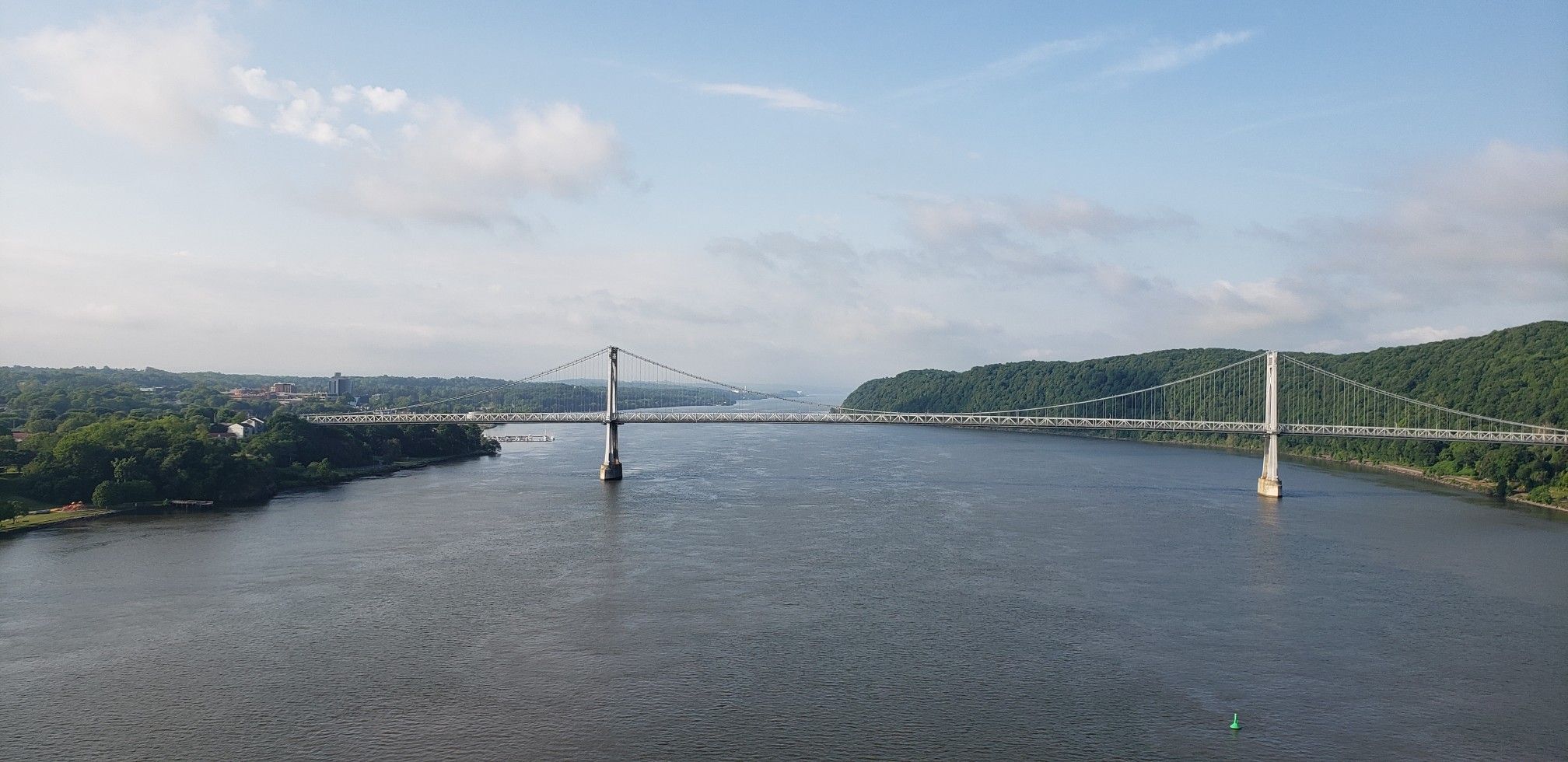 A suspension bridge spans a wide river with forested banks under a clear sky. - Walkway Over the Hudson – Hudson Valley Rail Trail loop from Poughkeepsie