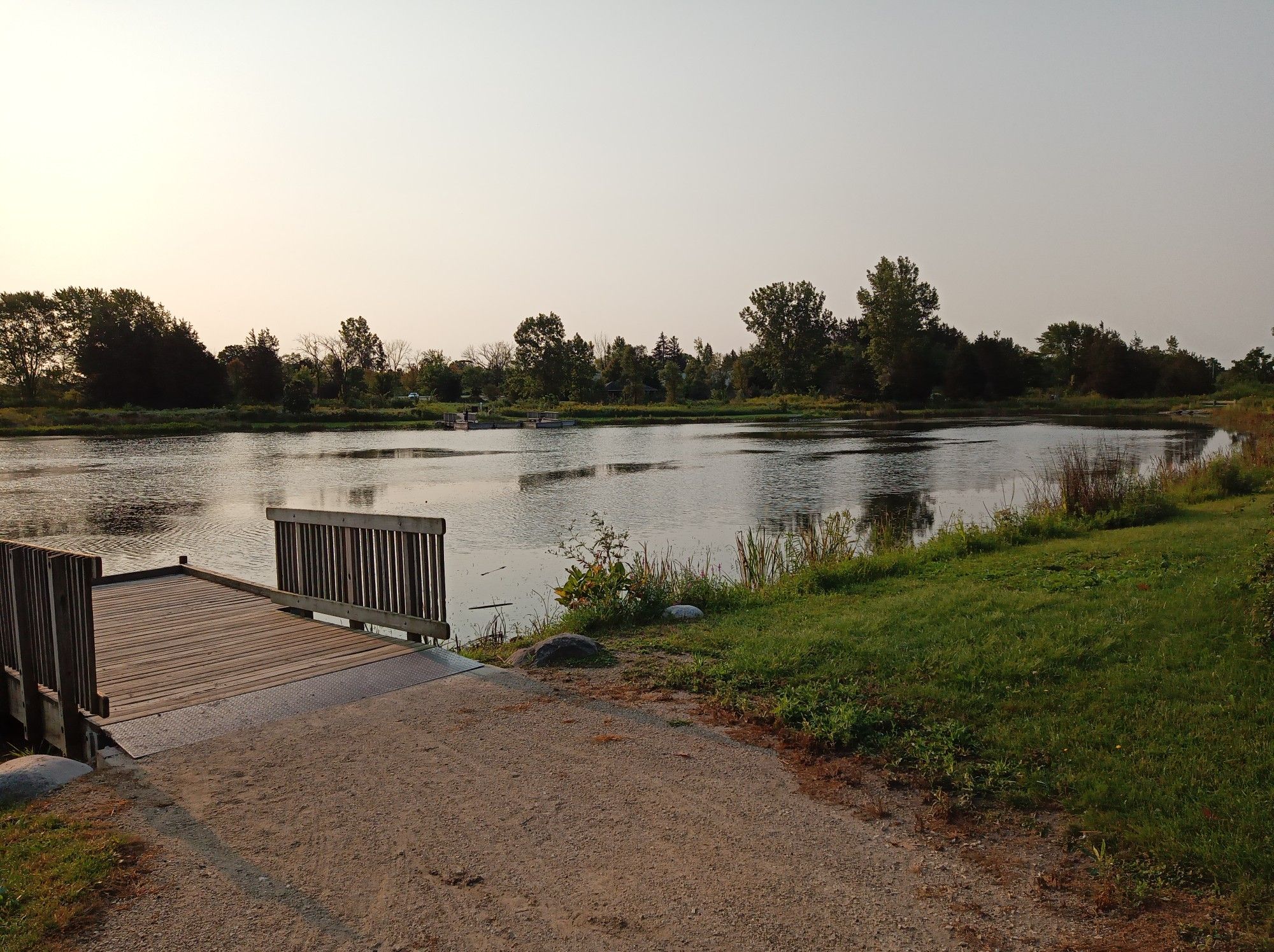 A wooden dock extends into a calm lake, surrounded by trees at sunset. - Nippersink Trail – Millennium Trail (Volo) loop from Hainesville