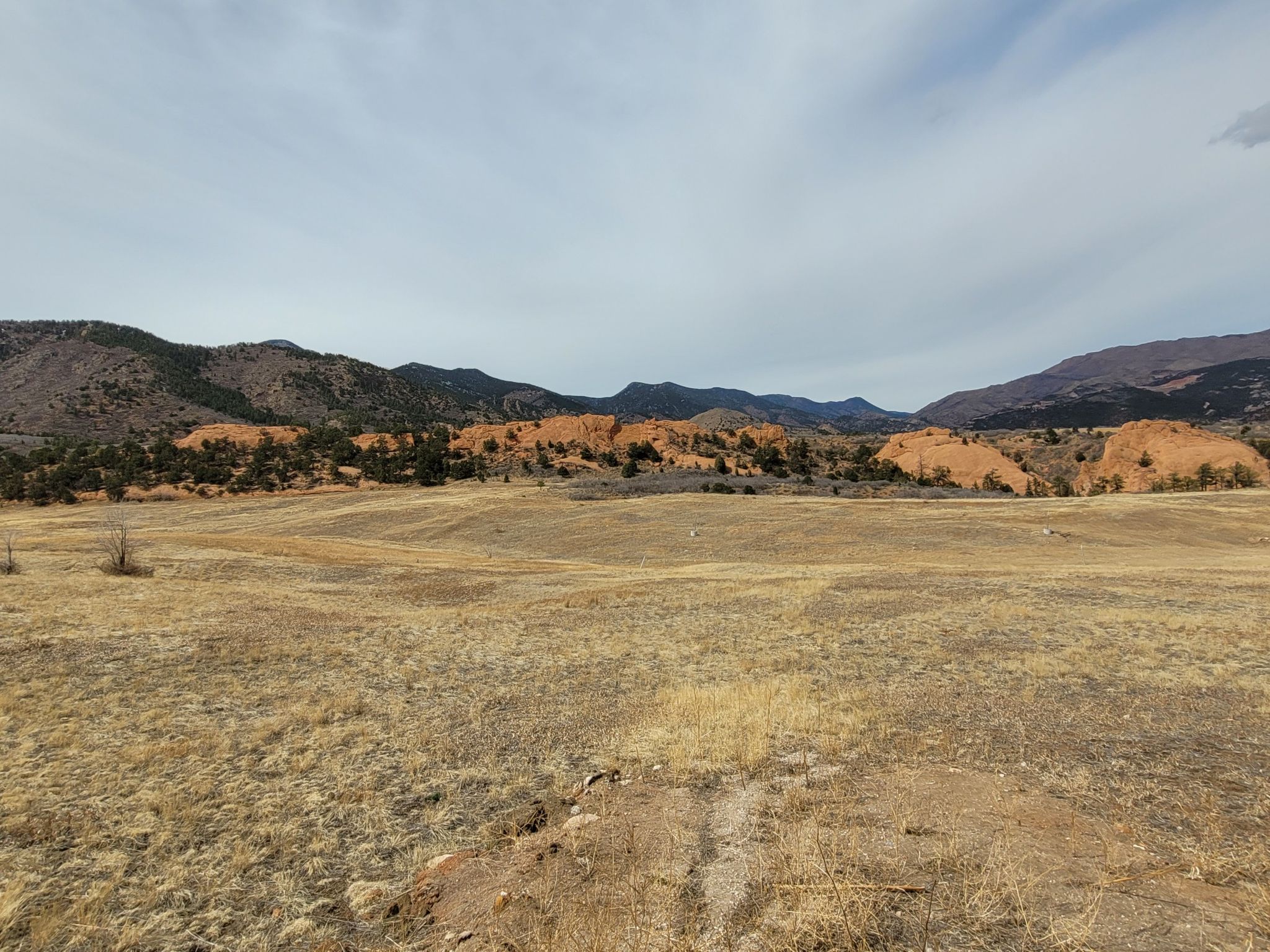 Vast dry grassy field with distant red rock formations and mountains. - Pikes Peak Greenway – Popsicle Bridge loop from Colorado Springs