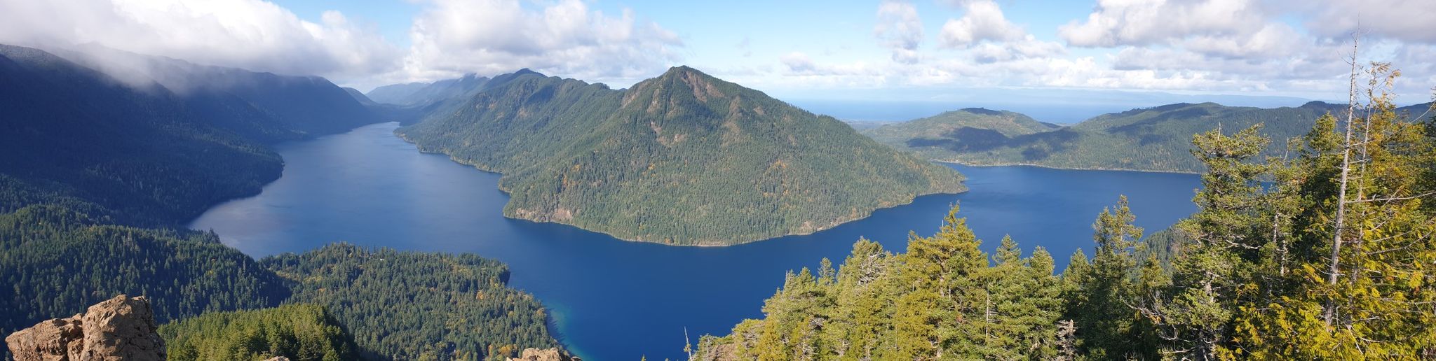 Panoramic view of a vast blue lake nestled among lush green mountains. - Mount Storm King Trail