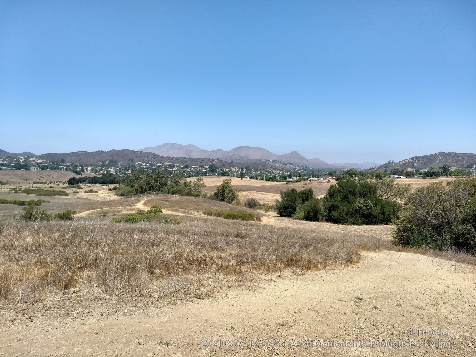 Expansive dry landscape with distant mountains and a town under a clear sky. - Boney Fossil Loop