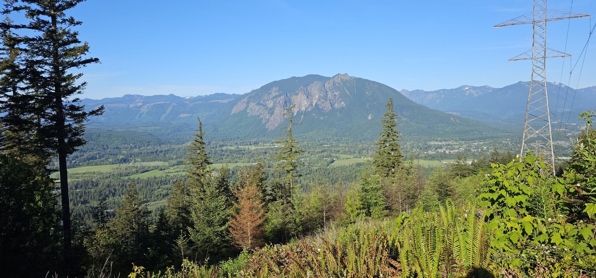 Panoramic mountain view with a valley, evergreen trees, and a power line. - Raging River Loop – Raging River State Forest