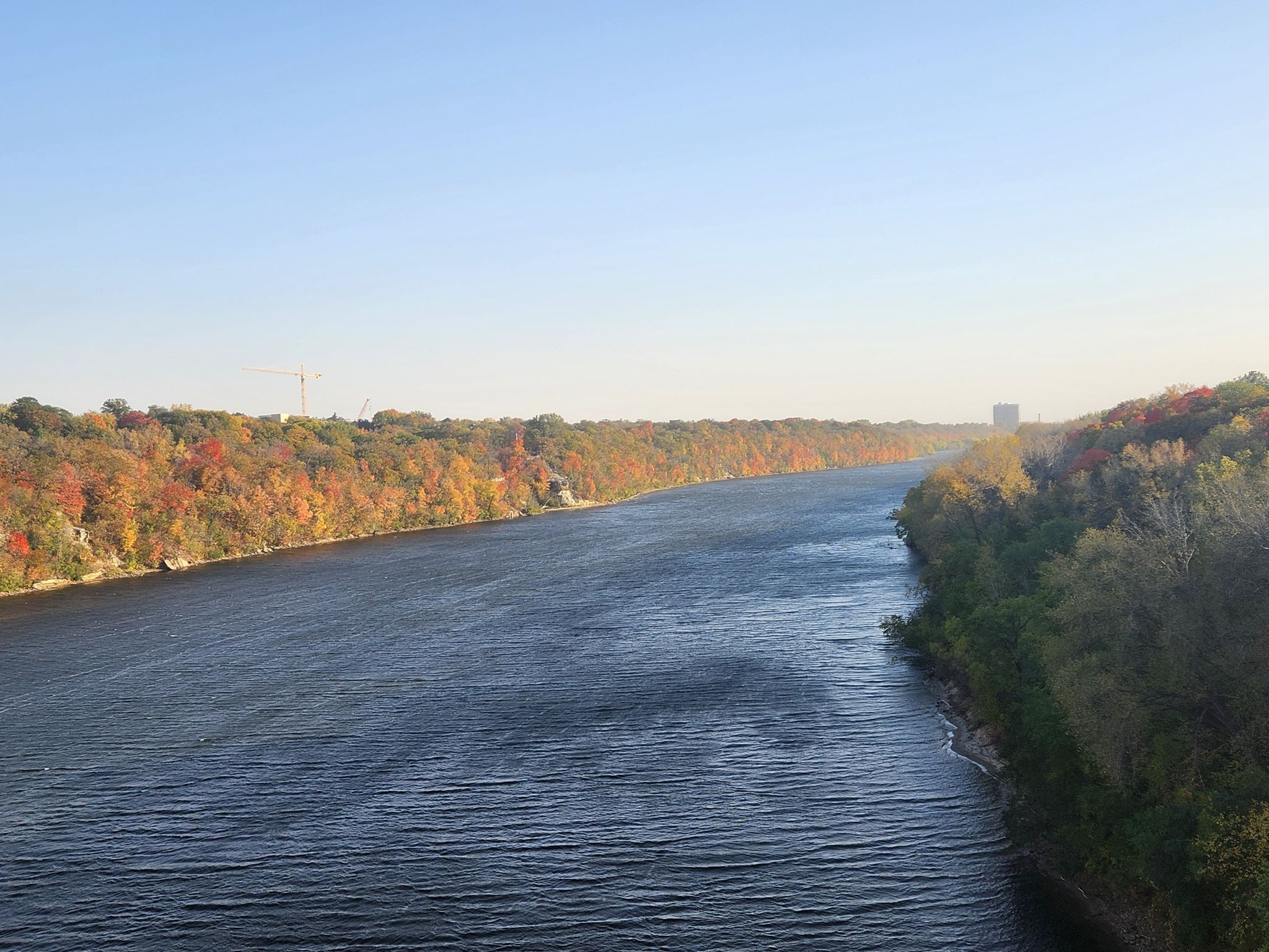 Wide river with autumn trees on banks under a clear blue sky. - Midtown Greenway – Martin Olav Sabo Bridge loop from 38th Street